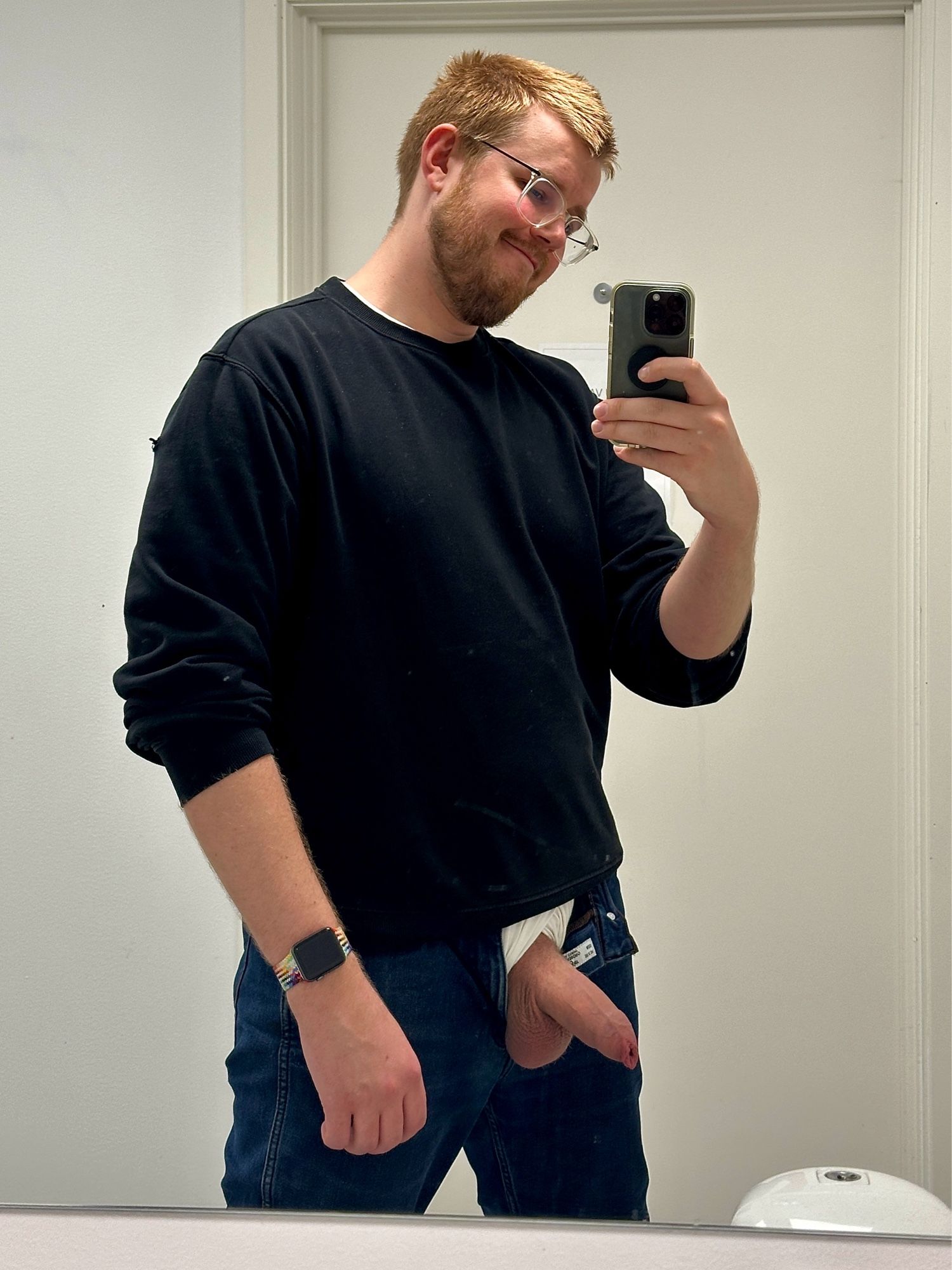 Man with short hair beard and glasses with his cock hanging out of his pants taking a selfie in the mirror