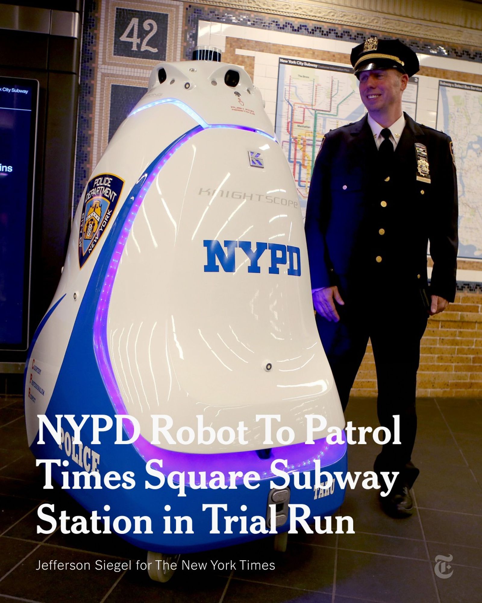 On a subway platform, a uniformed police officer is standing next to a robot on wheels that is roughly five feet tall and pyramid-shaped. The robot has a glossy white and blue surface that reads, “NYPD.” A headline reads: "NYPD Robot To Patrol Times Square Subway Station in Trial Run." Photo by Jefferson Siegel for The New York Times.