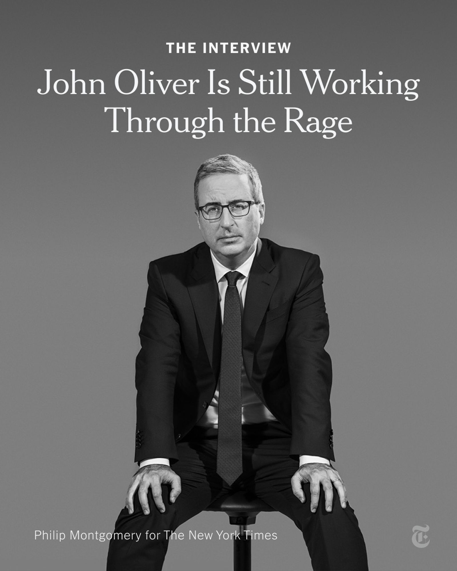 John Oliver, wearing glasses and a suit, is sitting on a stool with his hands on his knees. A headline reads: "John Oliver Is Still Working Through the Rage." Photo by Philip Montgomery for The New York Times