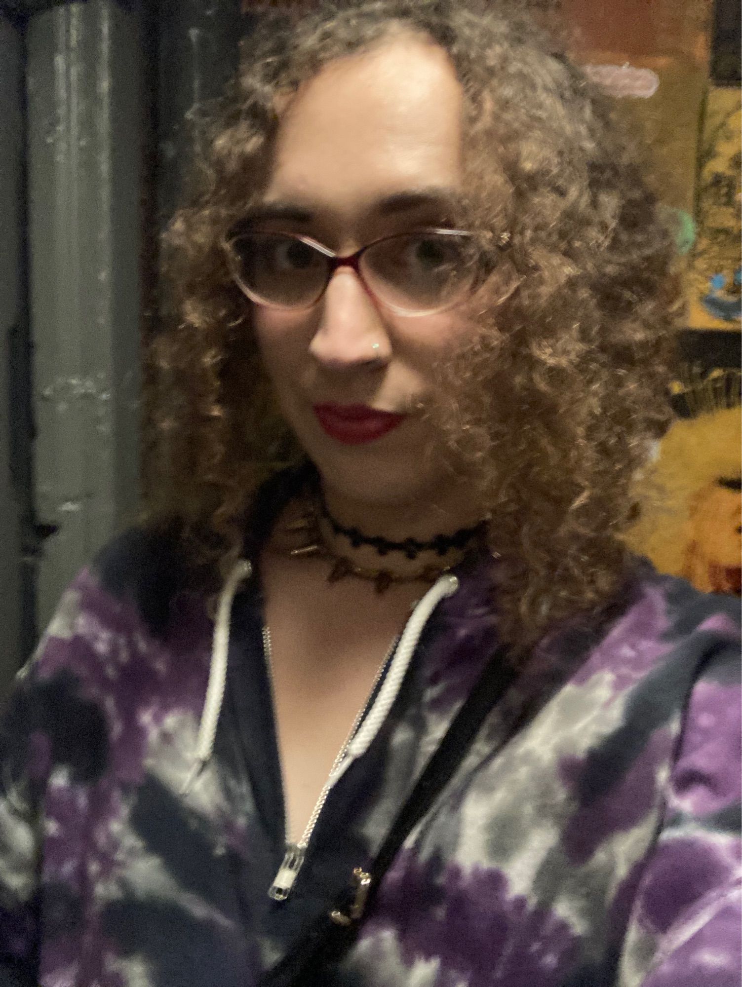 Sophia in a lesbian bar bathroom, hair up, in emo girl hoodie and jewelry. About to piss.