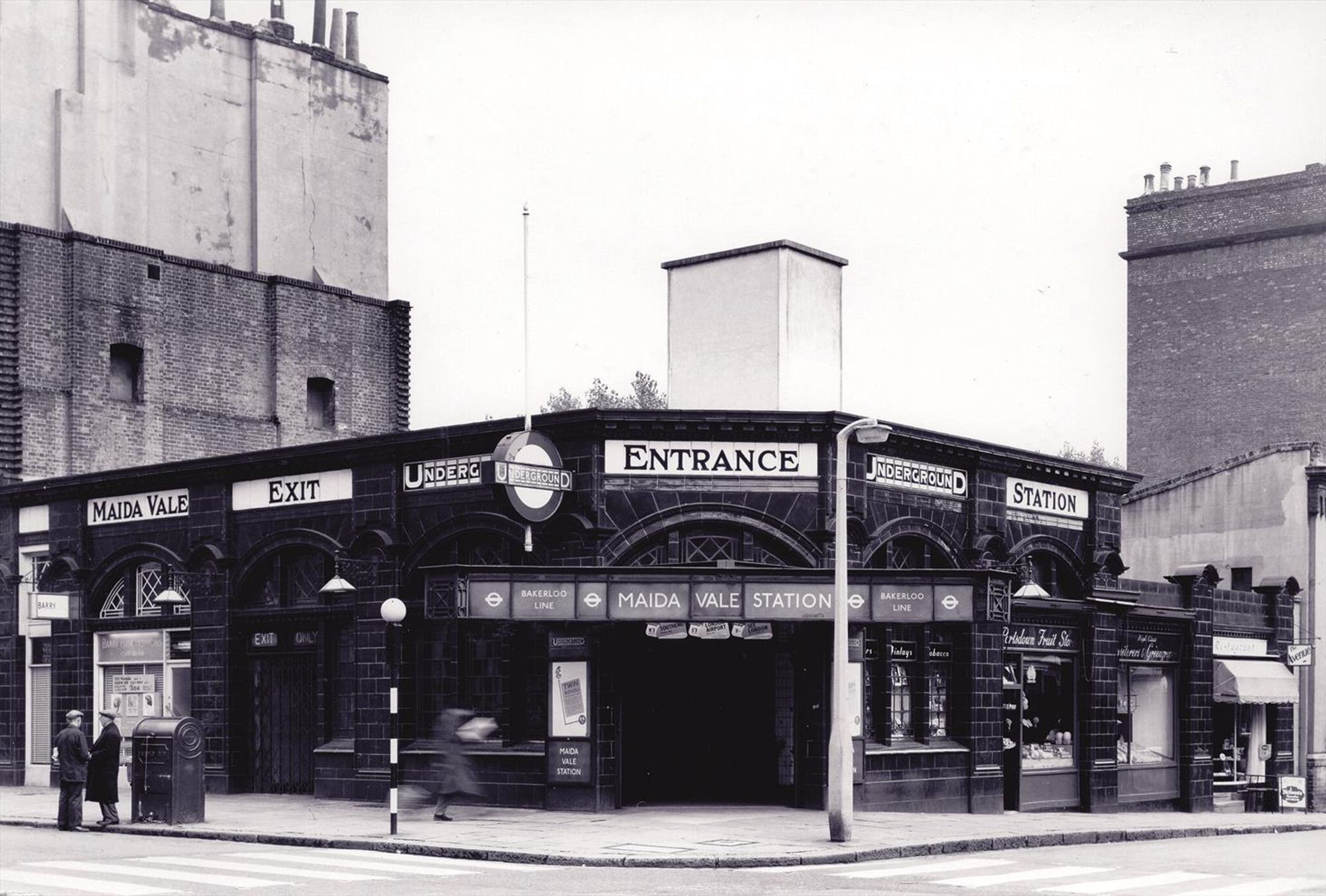 Maida Vale Tube station in the 1910s. It is a one story building with tiled walls and big signs indicating its a Tube station
