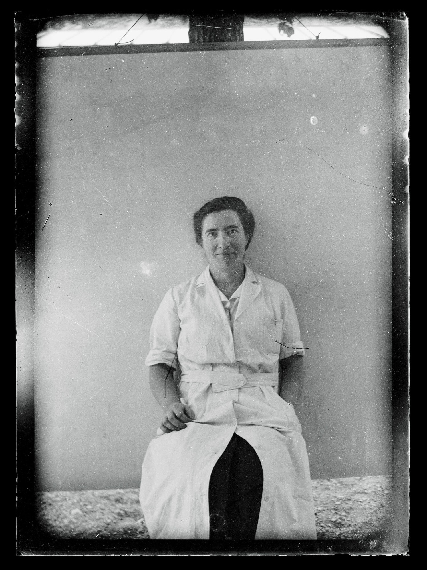 photo of Marguerite Perey in her long lab coat. She is a white woman with dark hair.