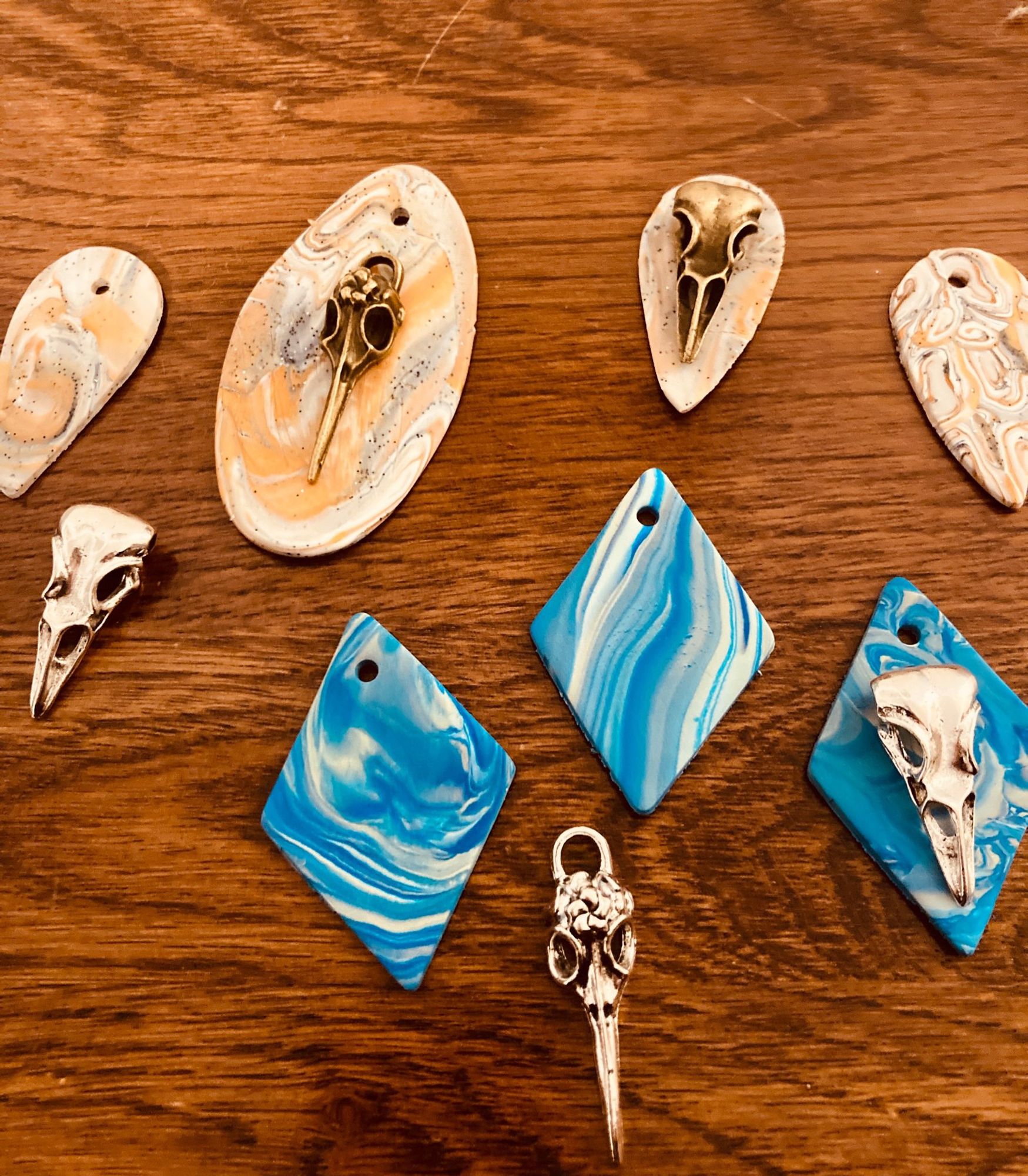 Brass and silver bird skulls with marbled polymer clay backs in the colors of a windy sky and a barn owl’s wing.