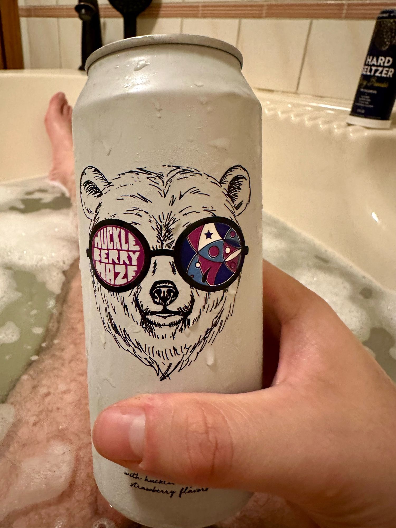 Closeup of the beer called “huckleberry haze”.  The logo is a bear wearing sunglasses with the name in the left lens.  The brewing company logo is on the right lens.  