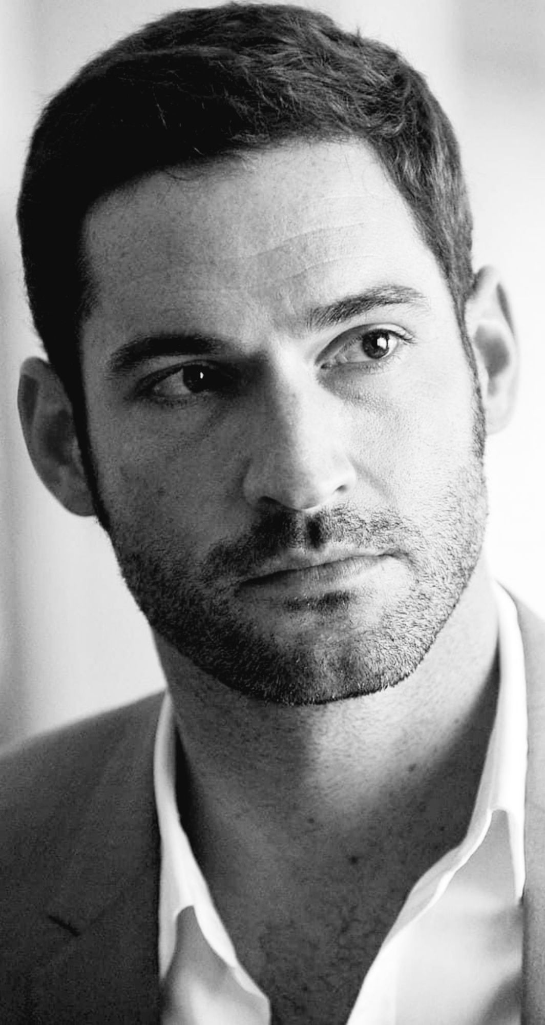 Black and white photo of Tom Ellis close up head and shoulders, looking slightly to the right with a thoughtfully serious expression. Taken circa 'Rush' era.