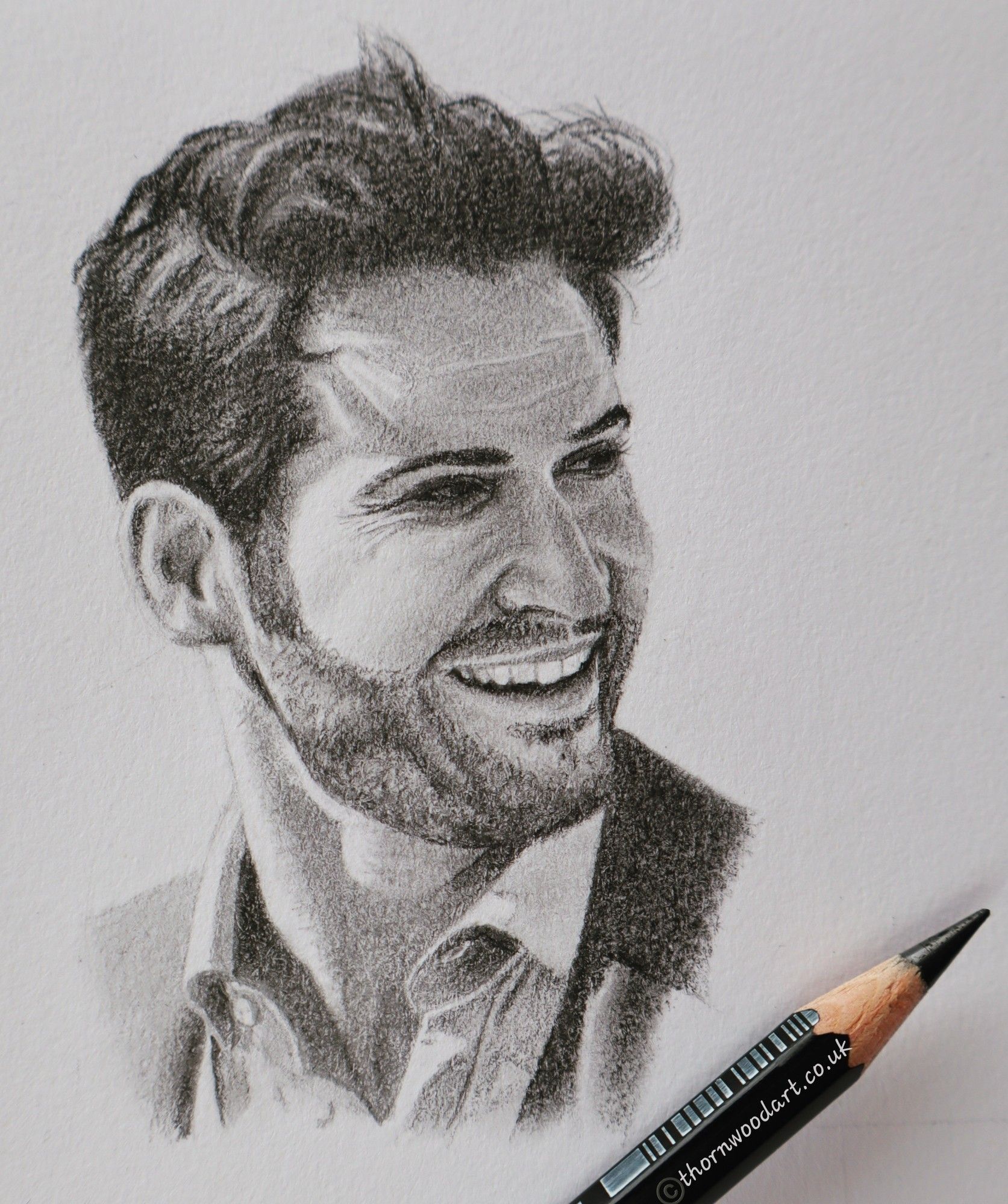 A pencil drawing with pencil laid on the paper to indicate its small size. Head and shoulders portrait of a carefree, smiling and windswept Tom Ellis as Lucifer Morningstar.