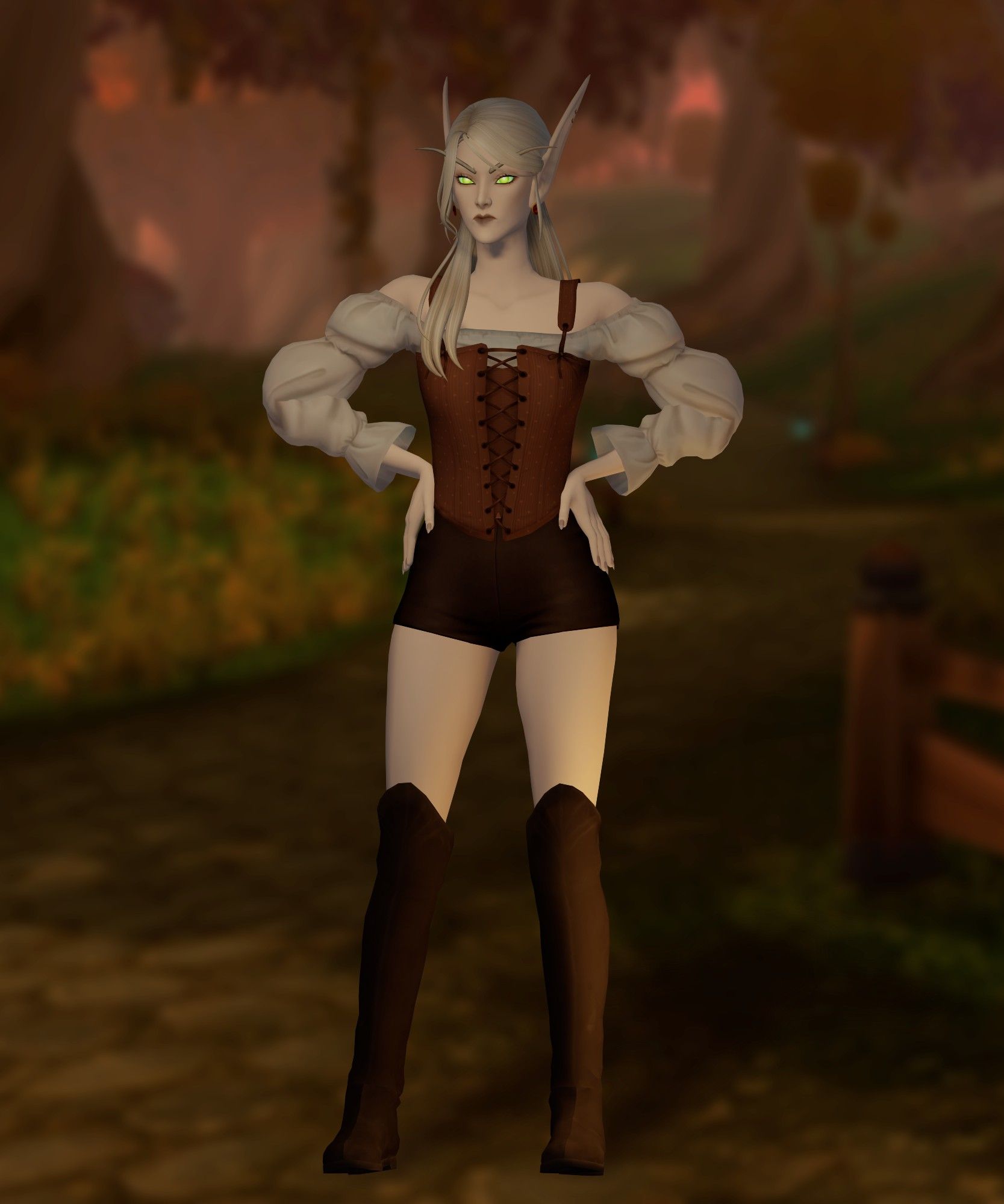 Blood elf render from WOW. Character is standing facing forward. She has glowing green eyes and a serious expression, with the same outfit—brown corset, white puffy sleeves, short pants, and knee-high boots. The setting remains the same, a warm-toned forest path in the background.