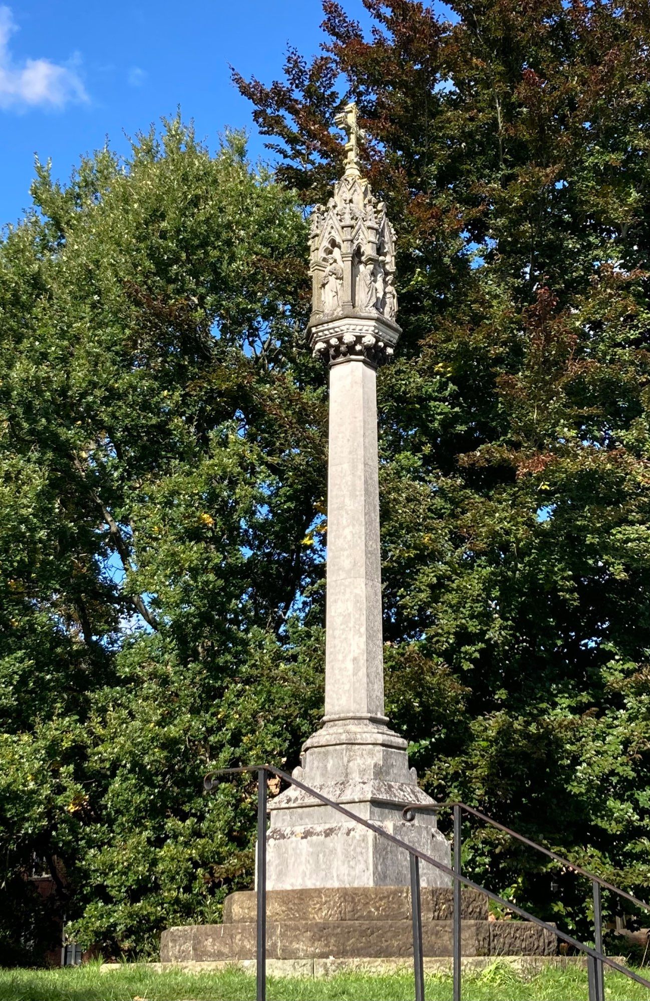 A stone column with carved figures and decoration at the top.