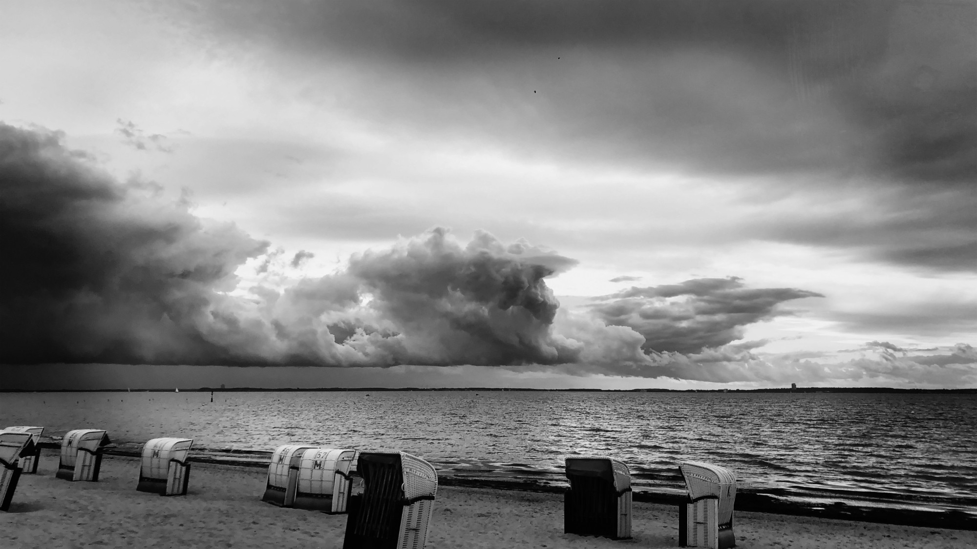 Pelzerhaken/Ostsee 05/19 - schwarz-weiß - im Vordergrund ein paar Strandkörbe, Sandstrand, dahinter die Ostsee und tief hängende Unwetterwolken 

Dieses Bild ist von mir lizenziert unter Creative Commons BY-NC-SA 4.0