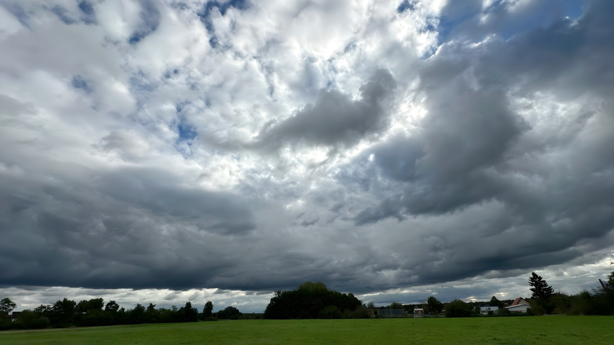 Ein wenig grün der Felder im Vordergrund, dann ein wenig Bewuchs und ein wilder Regenhimmel mit ein wenig Sonne dahinter 

Dieses Bild ist von mir lizenziert unter Creative Commons BY-NC-SA 4.0