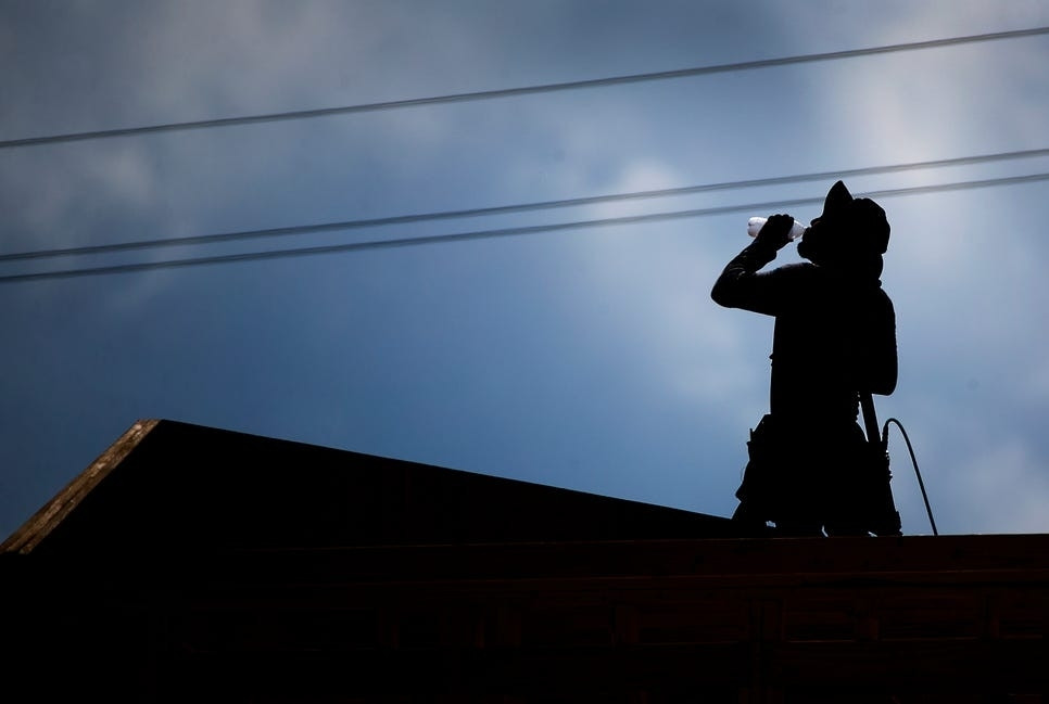 Worker taking a drink of water on a roof