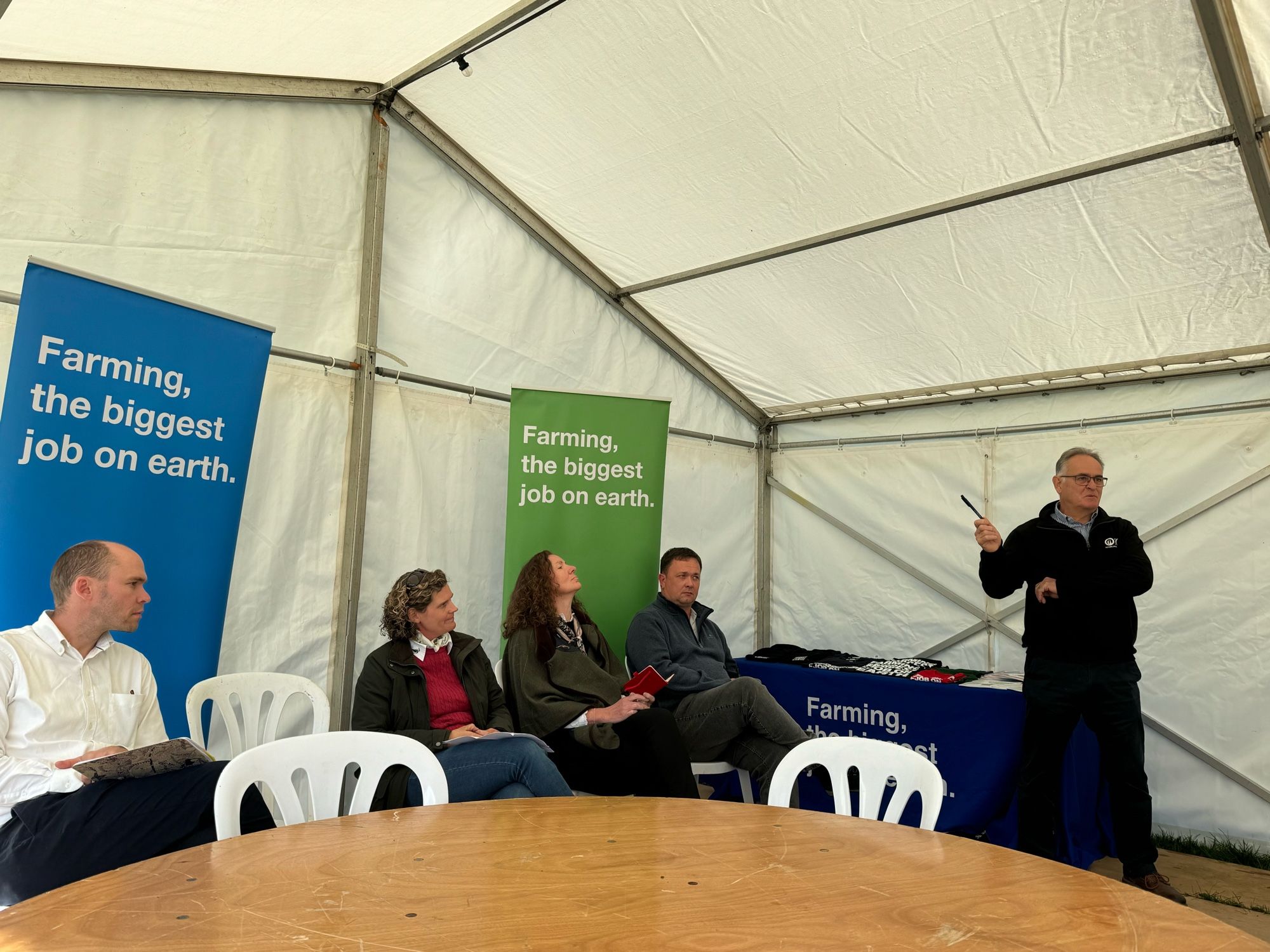 Four of the panel discussion sitting in marquee with the chair standing to the right of them.