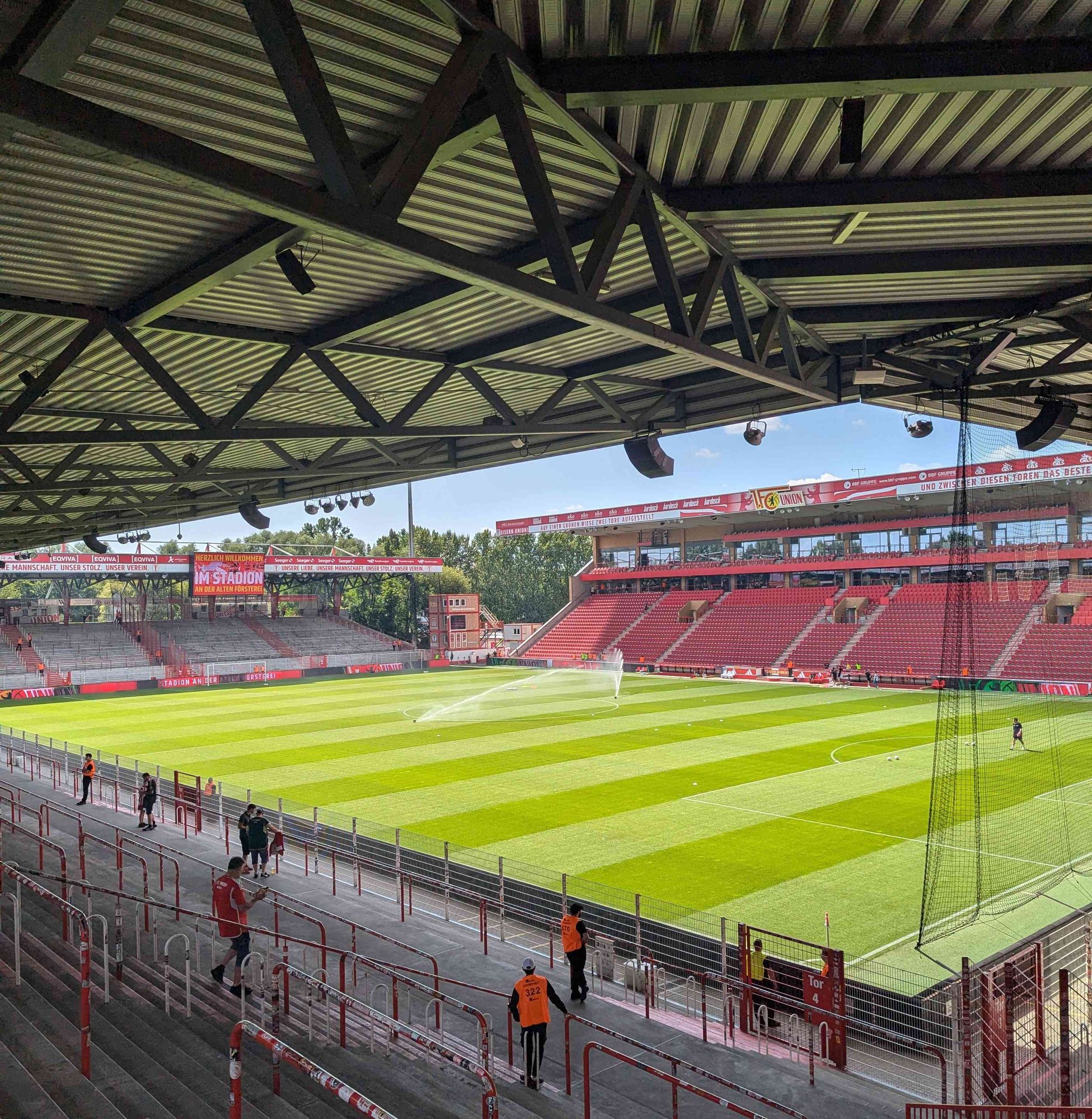 Blick von der Gegengerade auf das Fußballfeld des Stadions an der alten Försterei, die Haupttribüne und die Stehplatztraversen. Das Stadion ist noch fast leer.