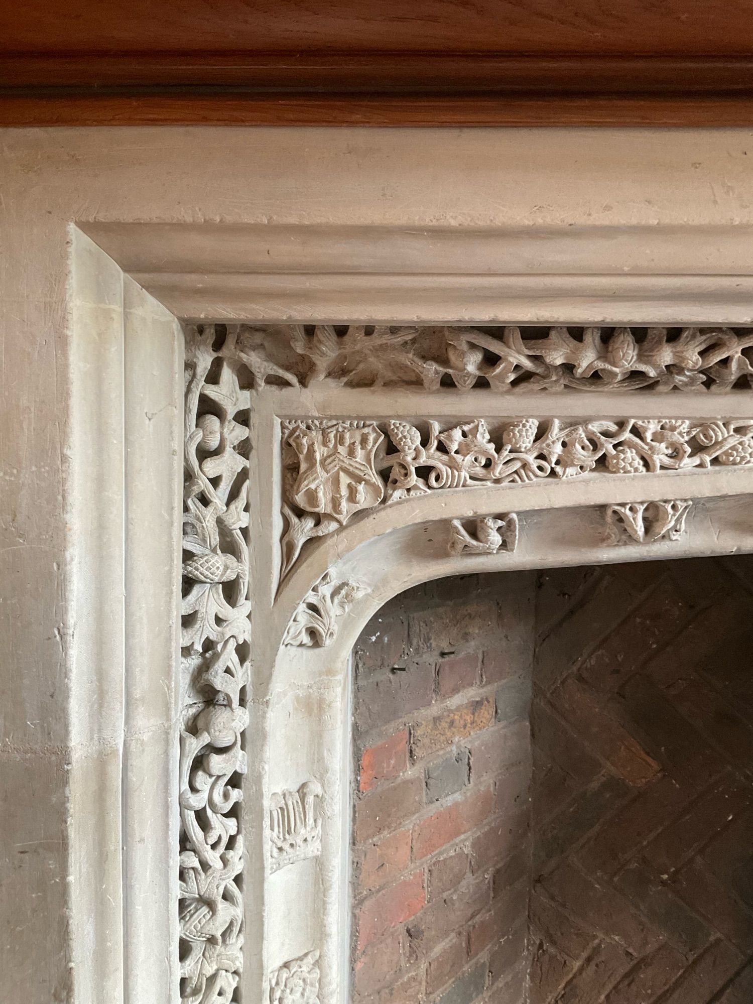 A carved stone fireplace with foliage and heraldry