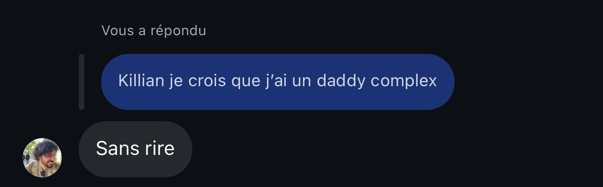 L'image montre une capture d'écran d'une conversation sur une application de messagerie. Il y a deux bulles de texte sur un fond sombre. La première bulle, en bleu, contient le message : "Killian je crois que j'ai un daddy complex". La deuxième bulle, en gris, en dessous, dit : "Sans rire". À gauche de la bulle grise, il y a une petite photo de profil représentant une personne.

Voici la transcription du texte :
1. "Killian je crois que j'ai un daddy complex"
2. "Sans rire"