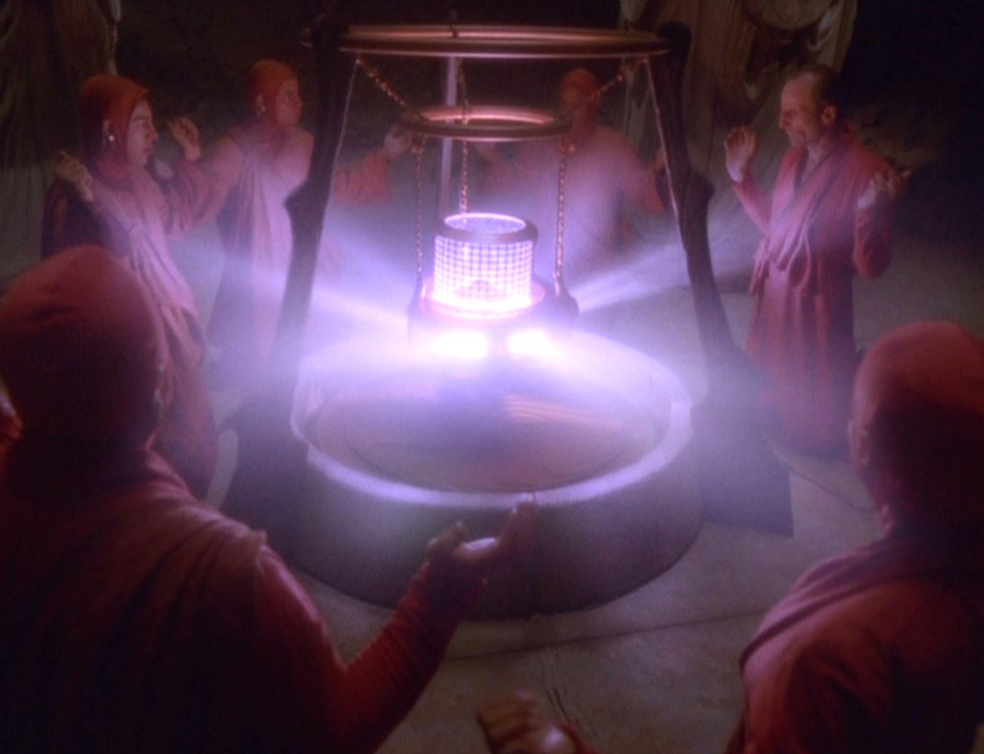 Bajorans in a circle doing some sort of ceremony with lights shining in the middle.