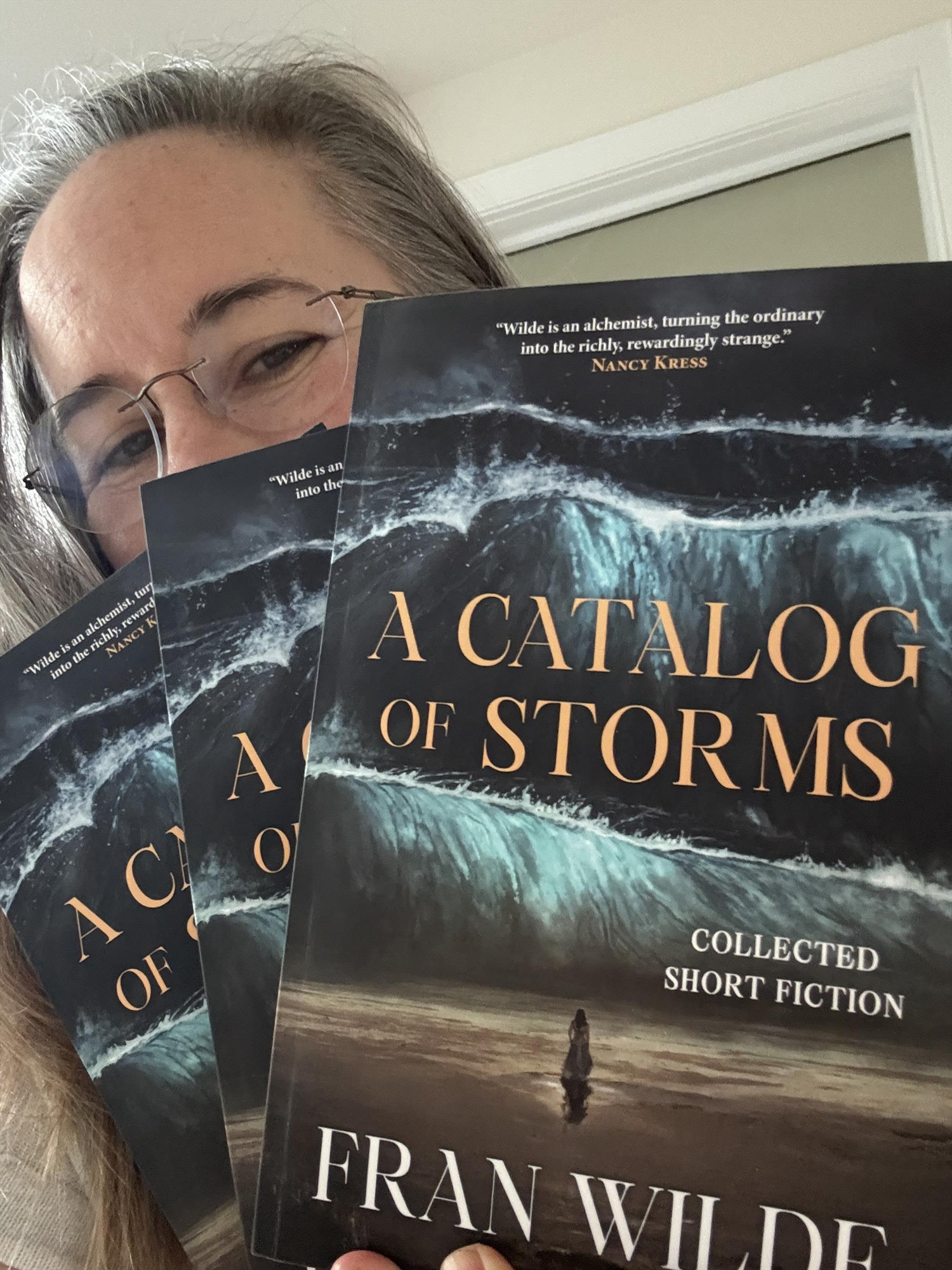 Author holding three finished copies of A Catalog of Storms by Fairwood Press