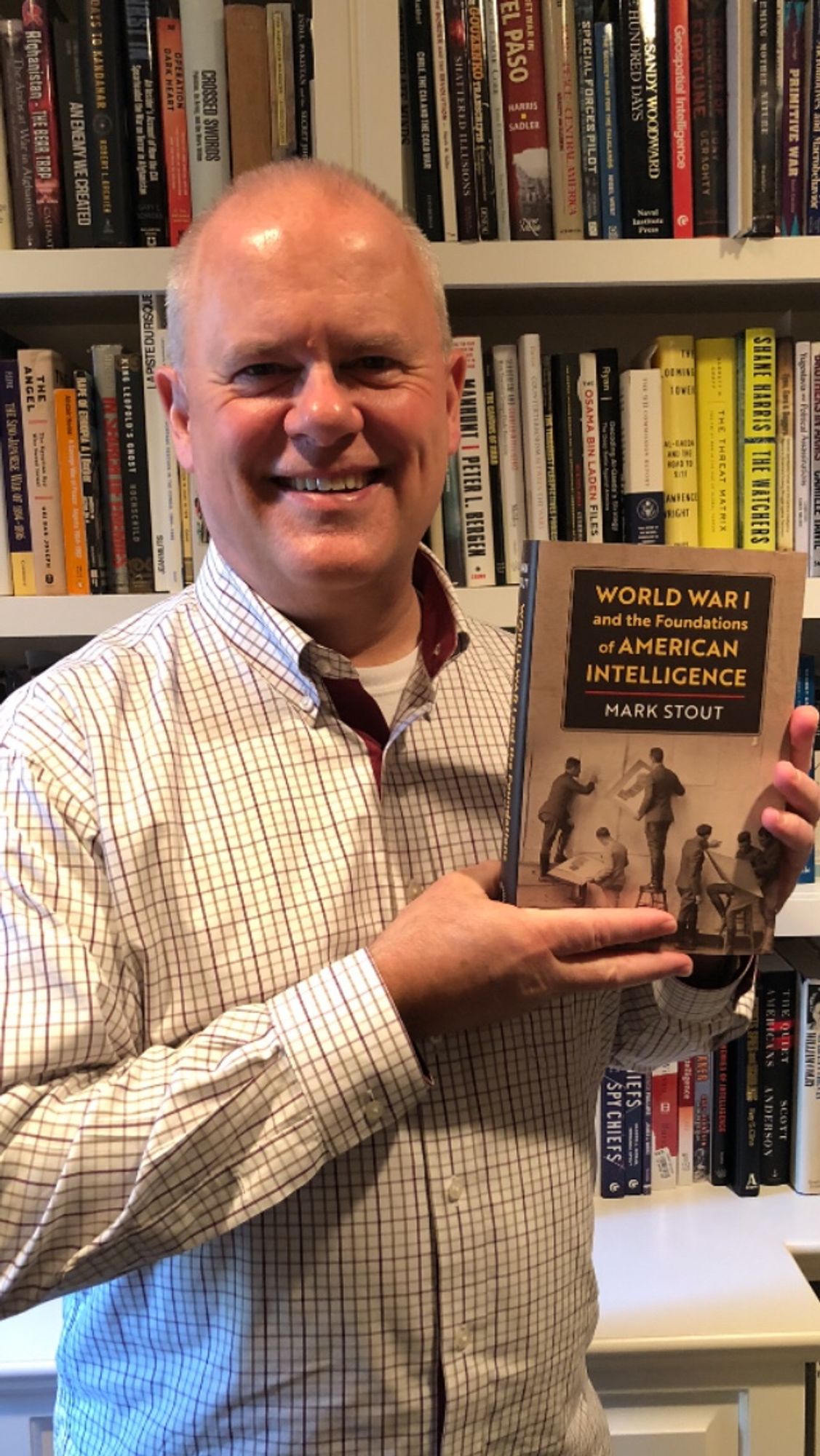 Me, standing in front of a bookshelf holding a copy of my new book “World War I and the Foundations of American Intelligence.” I have a big grin on my face because OMG this took soooo long.