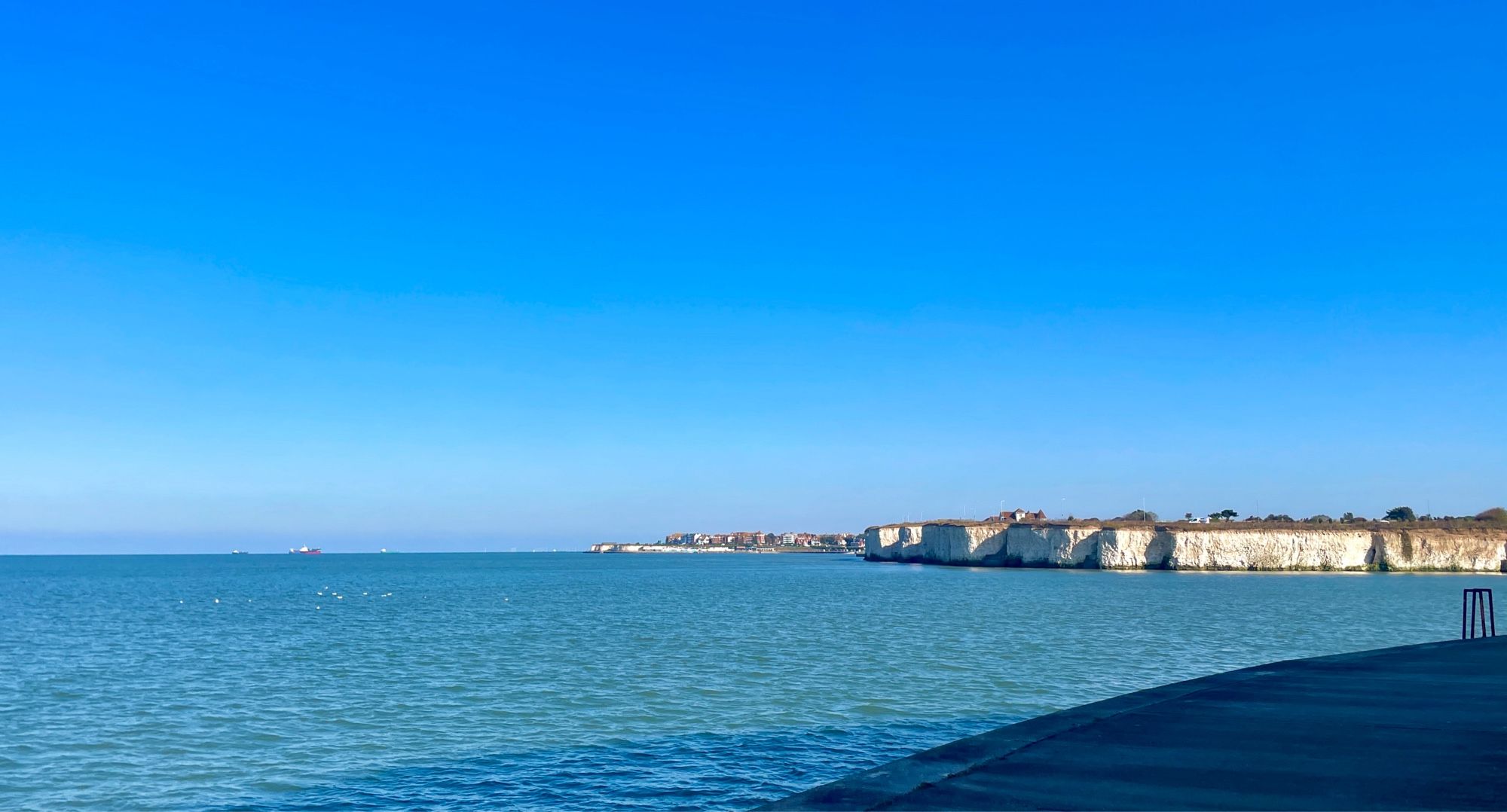 Bike touring amongst white cliffs seaside sandwiched by bright blue skies and bright blue waters