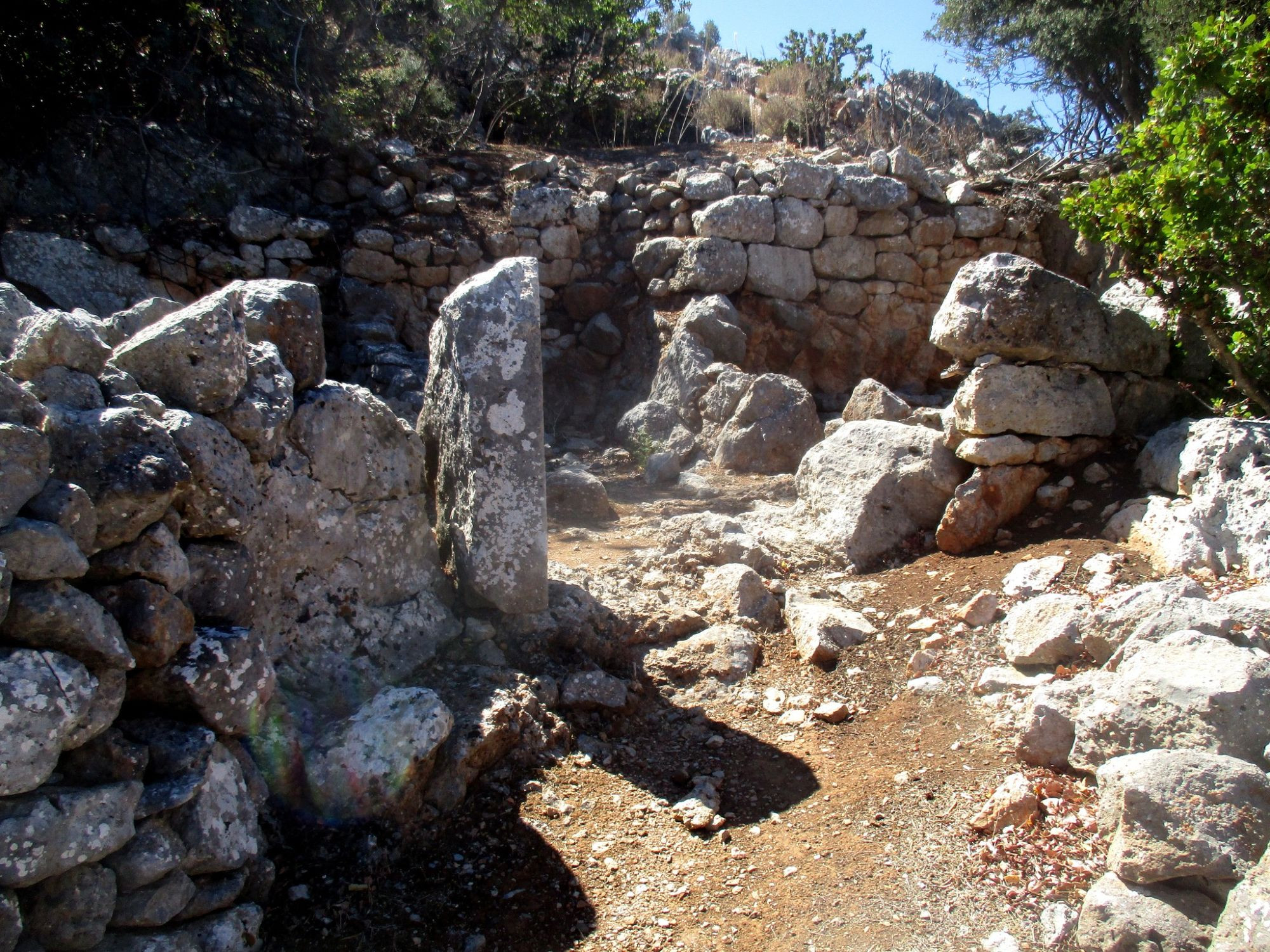 Etwa 1,60 m hoch, erhaltene Ruine aus hellem grauen Stein. Hausgrundrisse sind zu erkennen, sowie ein Längssein, der einmal die linke Seite eines Türrahmens bildete. Es handelt sich um Trockenmauerbau.