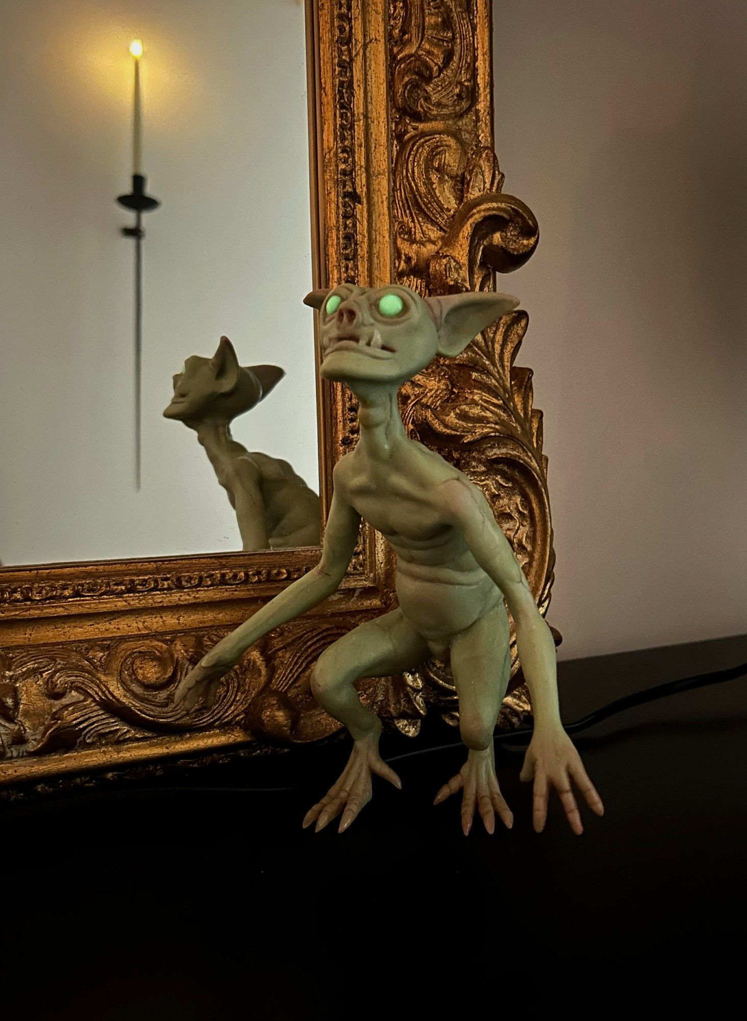 photo of a goblin sculpture by Cocoon Toys. The goblin is pale green with glow-in-the-dark eyes