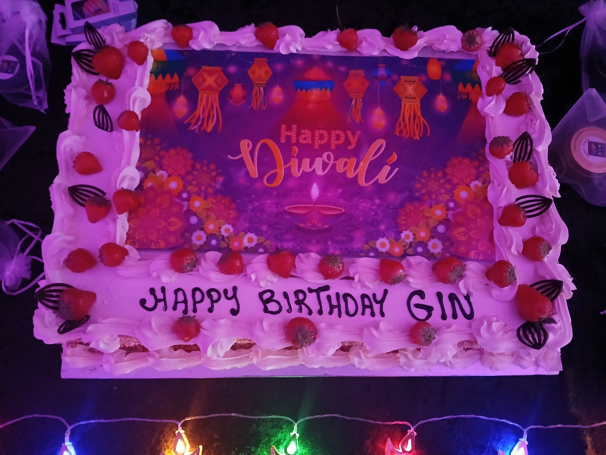 Large rectangular birthday cake with white frosting, covered in strawberries with text that reads Happy Diwali and Happy Birthday GIN