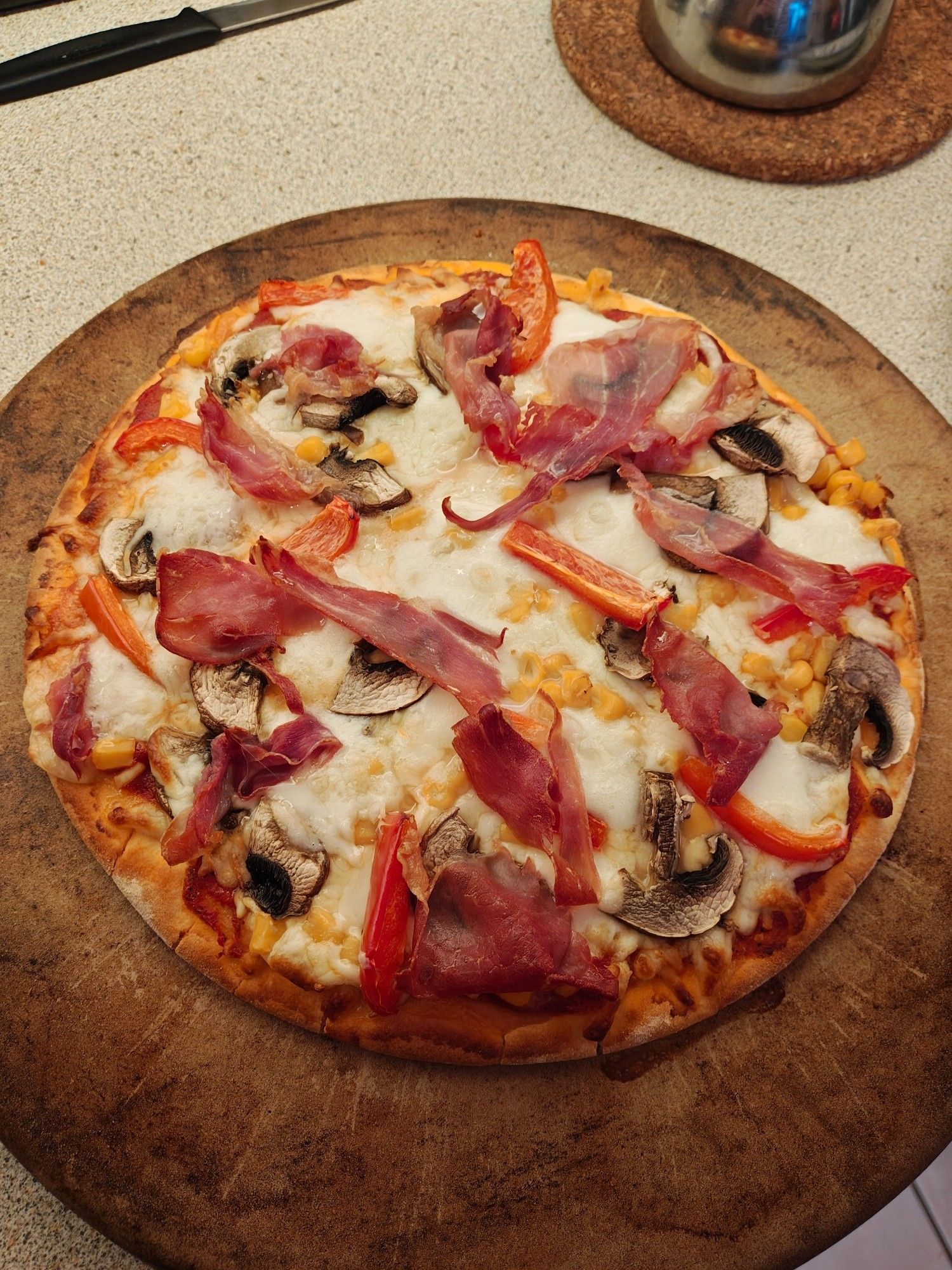 A gluten free base pizza, topped with lots of cheese, mushrooms, sweetcorn, red peppers and Parma ham.