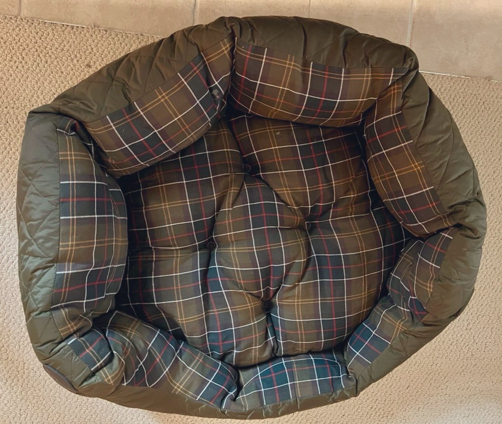 Photo of a dark green plaid dog bed.