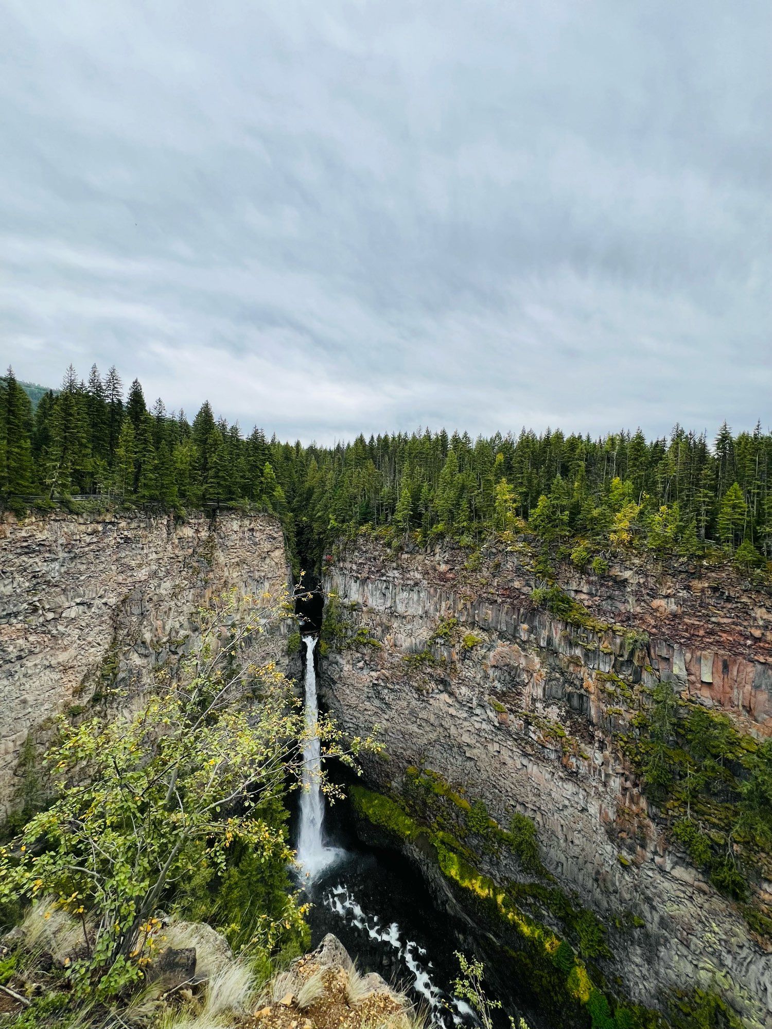 Photo of a waterfall with steep cliffs and forest surrounding it.