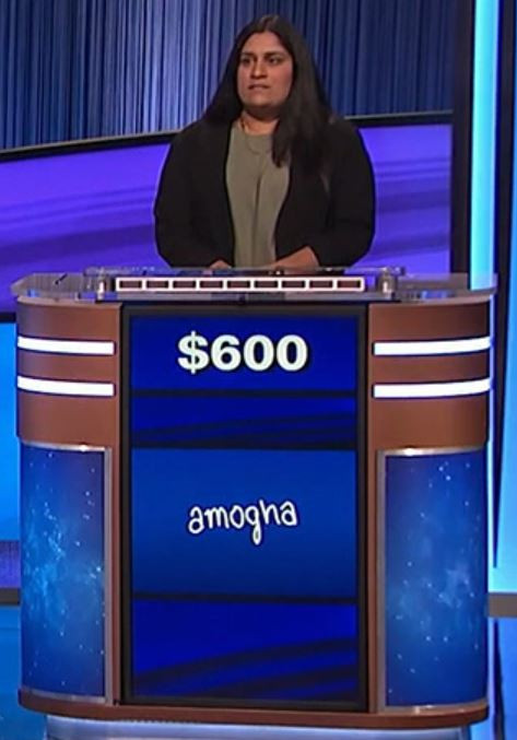 A woman on Jeopardy with the name "Amogha" written on the screen of her lectern