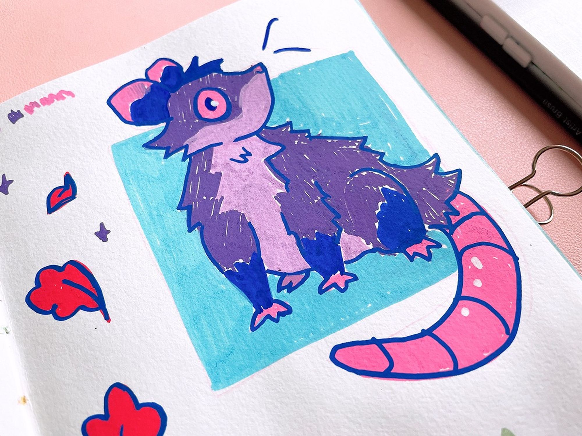 An opossum looking shocked. It is sitting with a blue box border. Small leaves are doodled on the side.