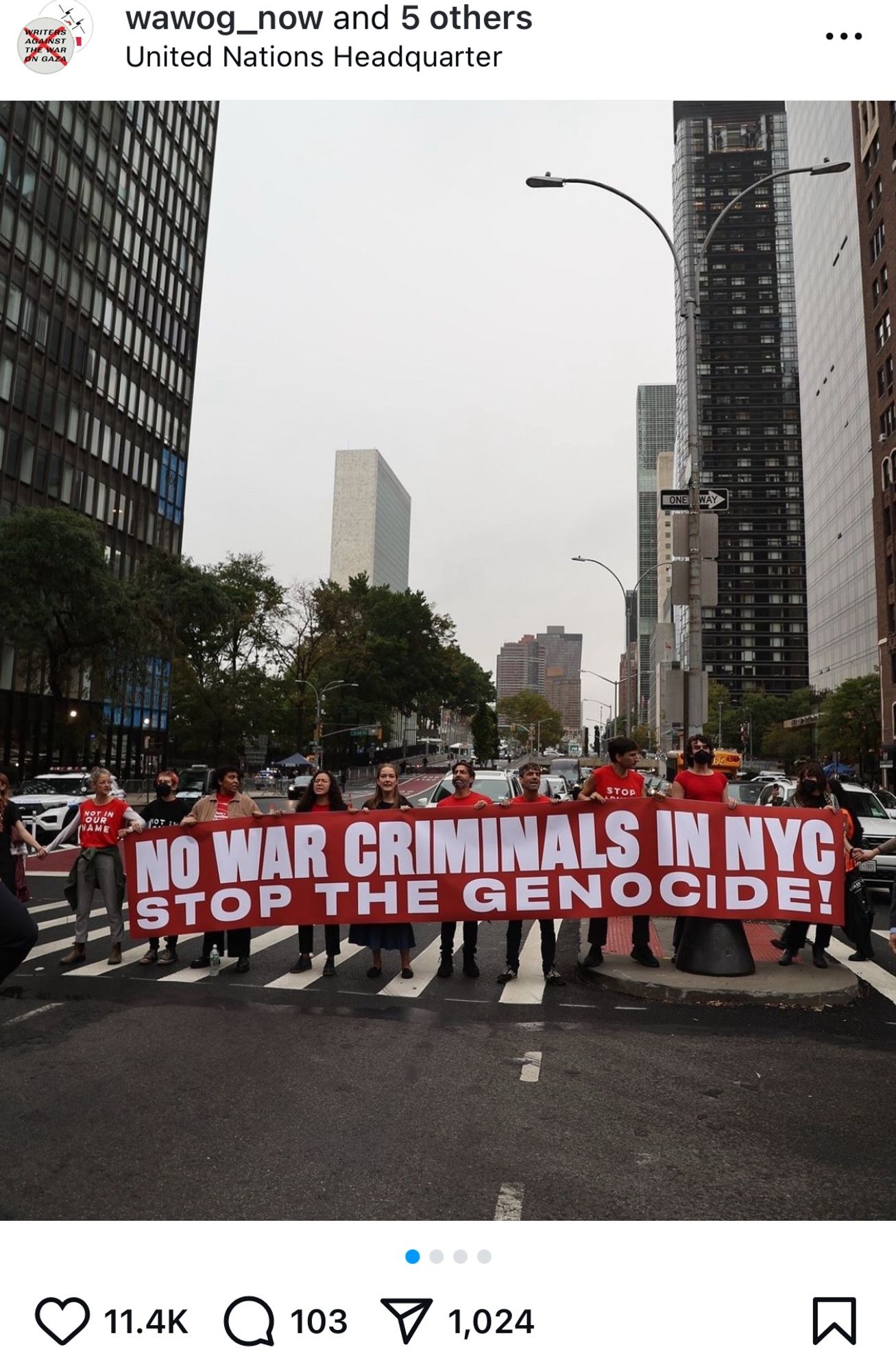 members of multiple antiwar organizations wear red shirts, standing shoulder to shoulder on third avenue on a wet wednesday morning in new york, holding an enormous red banner with white lettering that reads
NO WAR CRIMINALS IN NYC
STOP THE GENOCIDE!