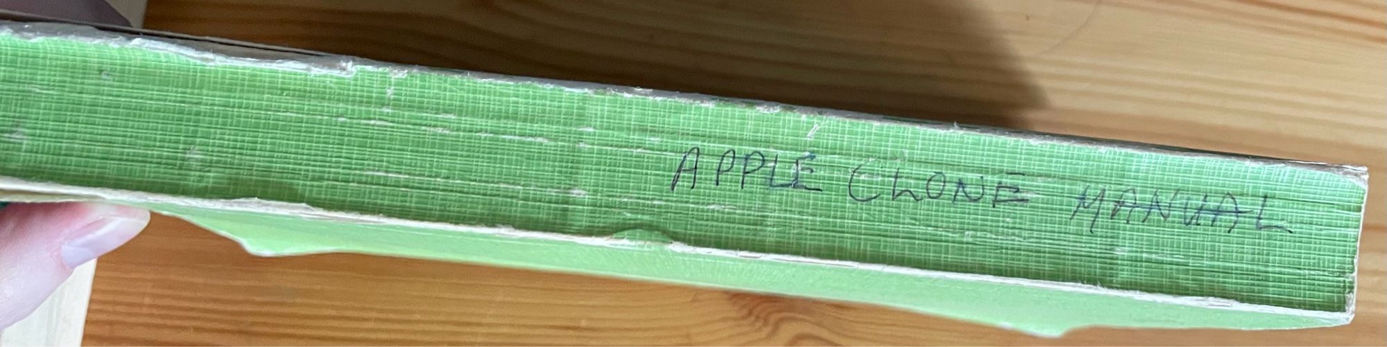 A green book with the title “Apple clone manual” handwritten on the spine.