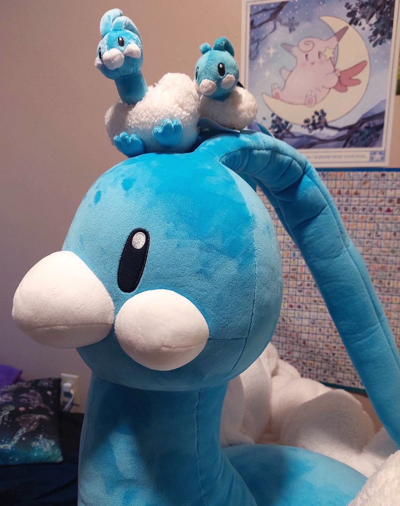 A giant Altaria plush. Sitting atop its head are two much smaller Altaria plushies.