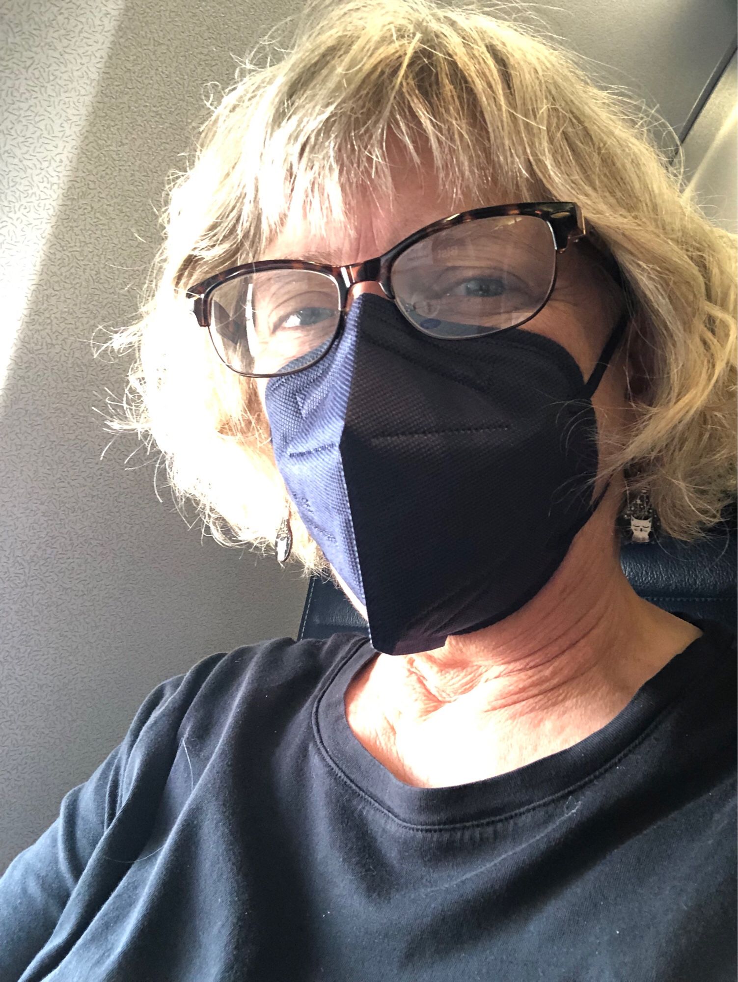 Picture of Heidi B. Hammel on an airplane, wearying a black shirt and a dark blue face mask.