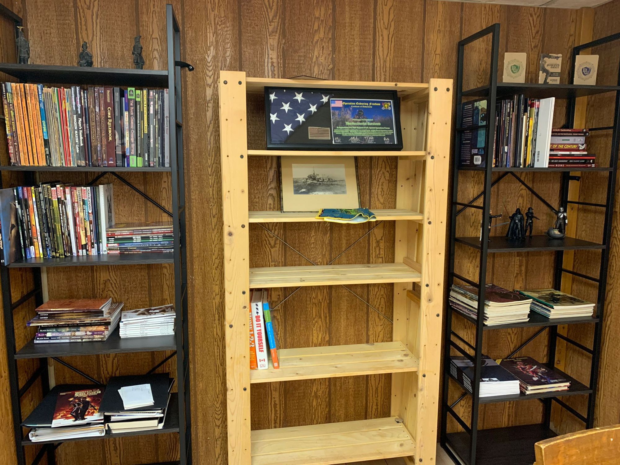 One side of a room with three shelving units, two with lots of books and the middle one pretty empty.