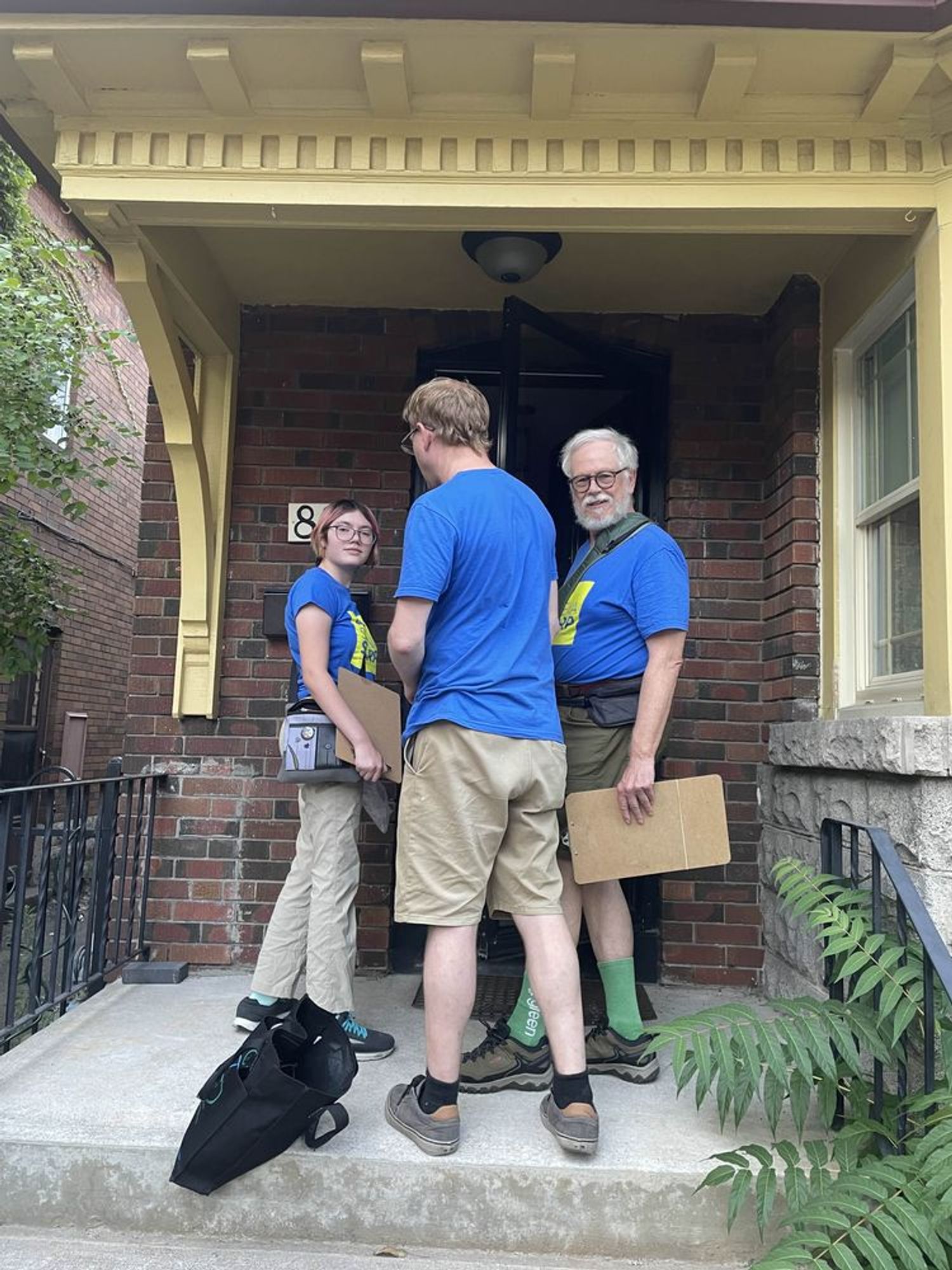 Canvassers for Sheena Sharp on the door step of a red brick home.