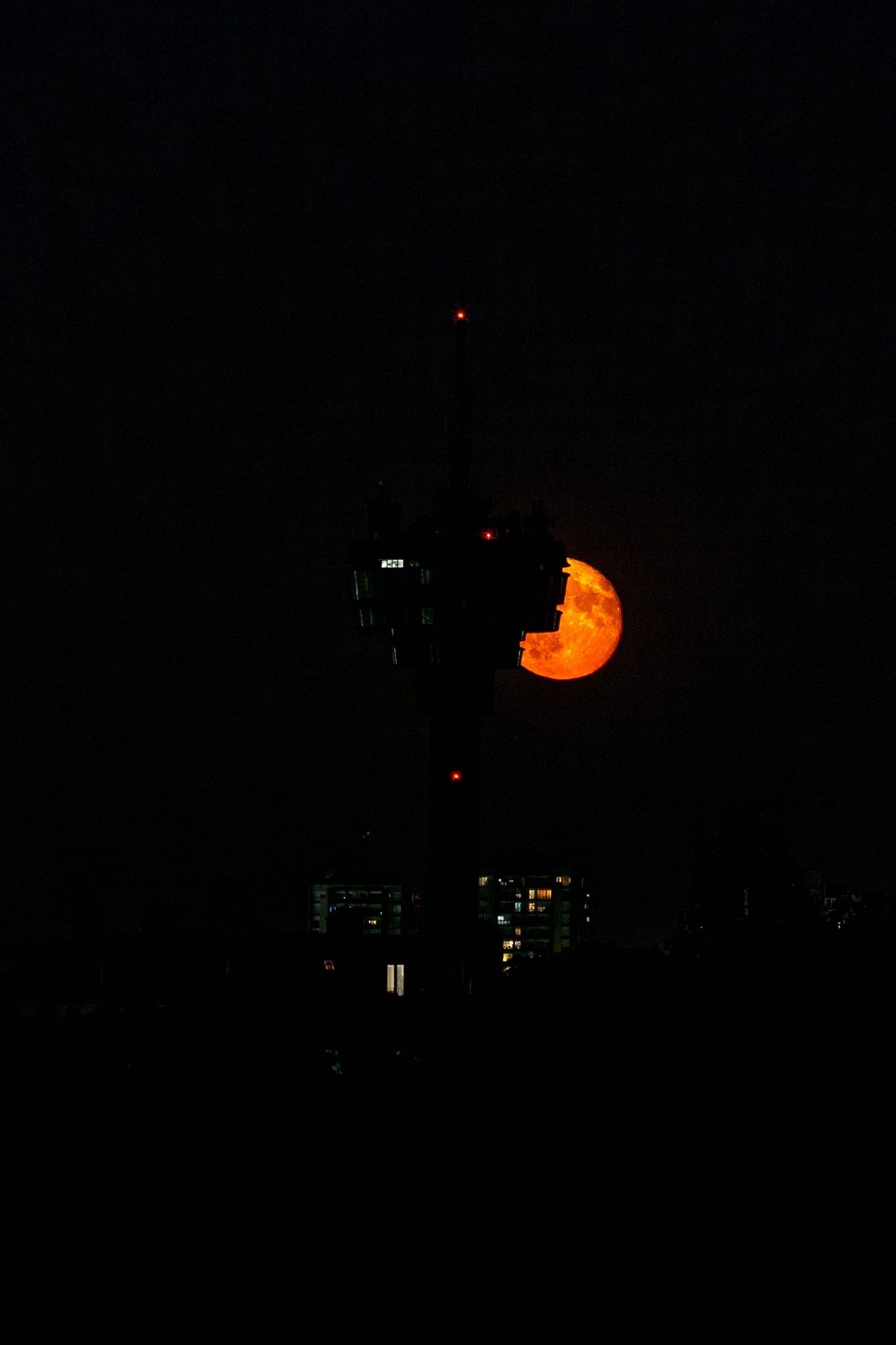 Lune rouge se levant derrière une tour