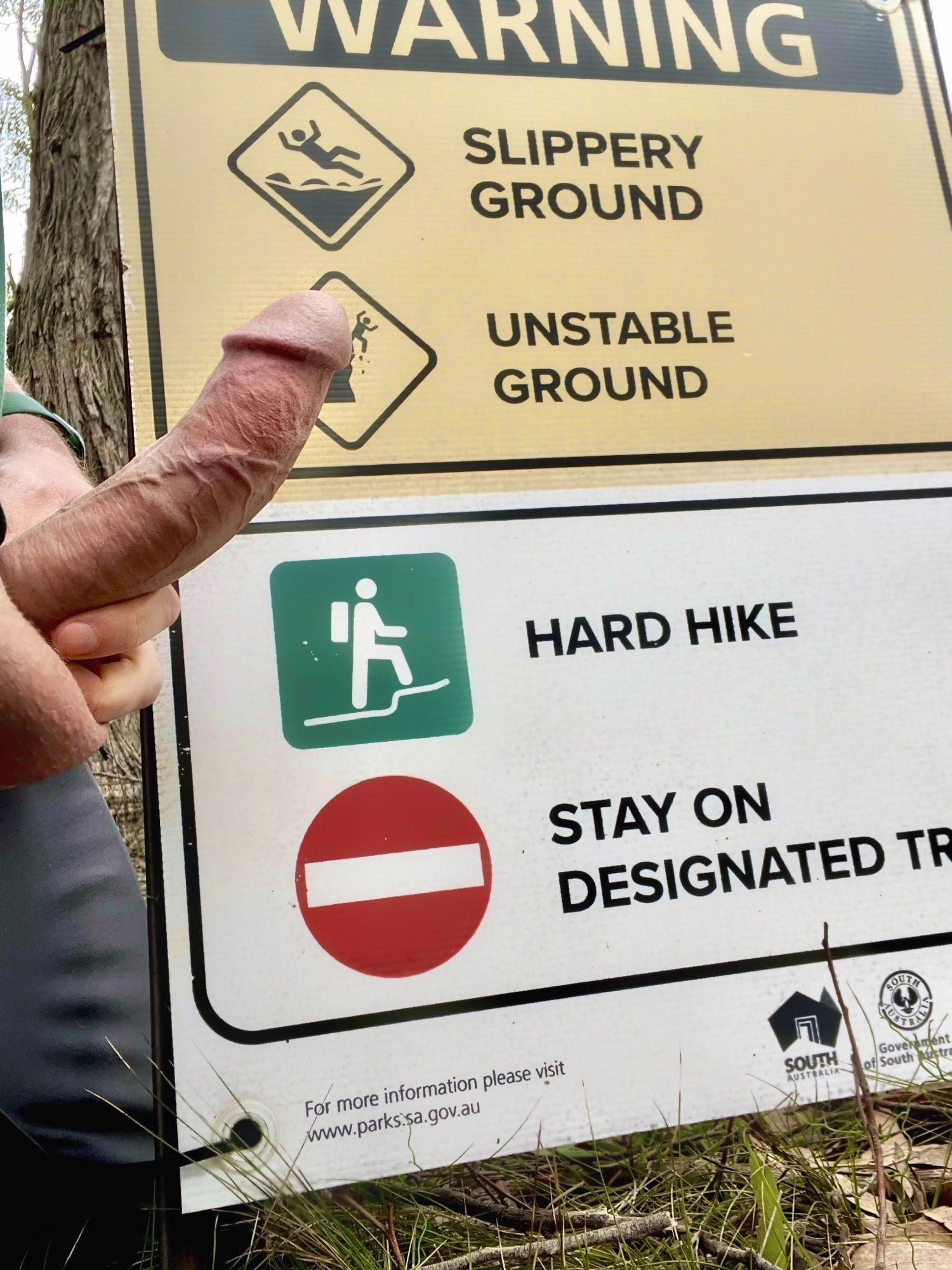 A hard cock in front of a sign warning about a hard hike