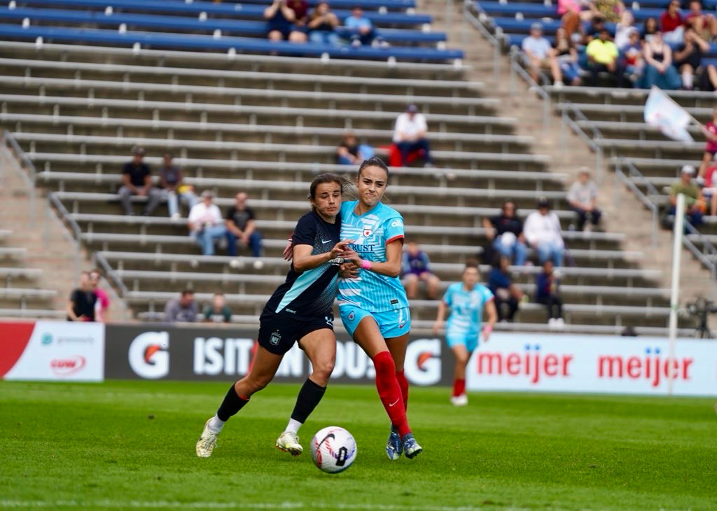 Julia Grosso and nealy Martin race for the ball. It appears they are engaged in a ballroom dance. 