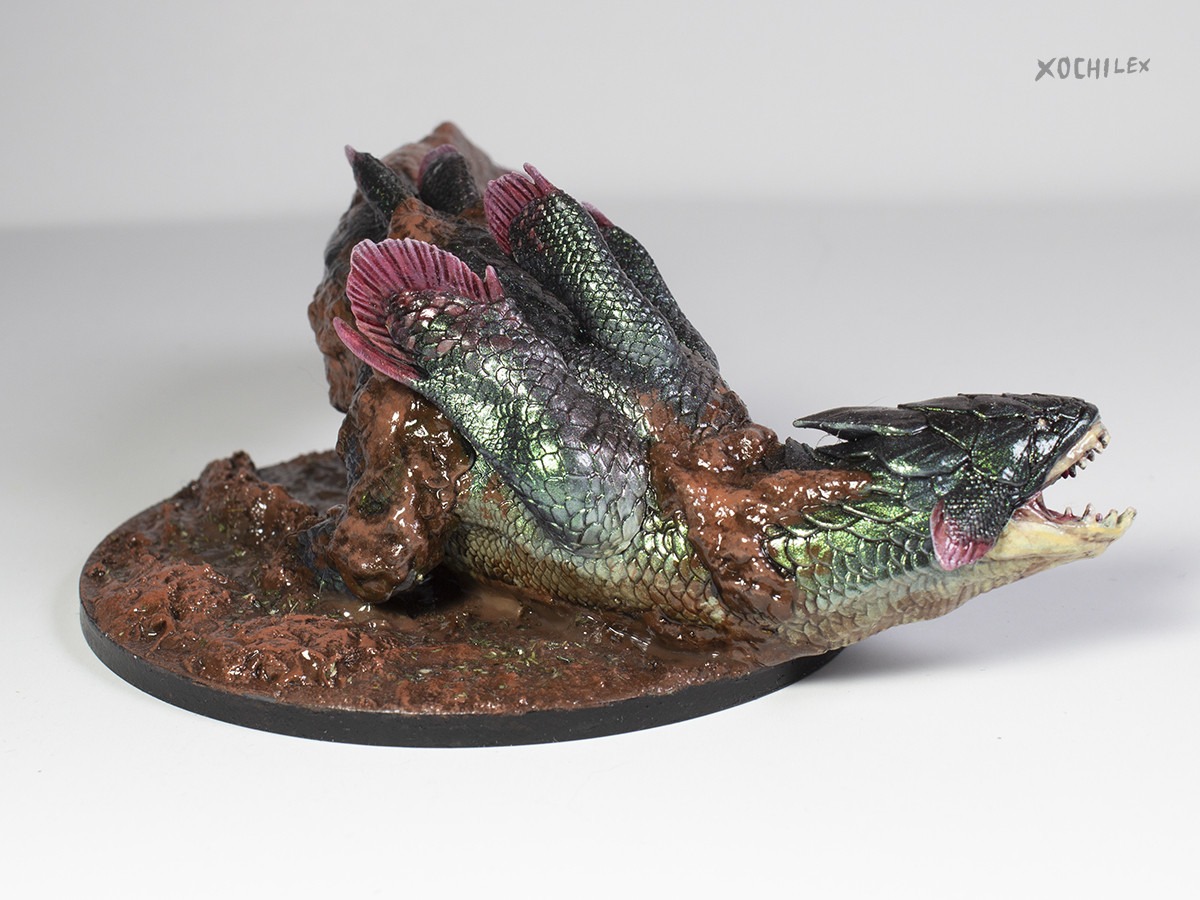 A fish-like creature with shiny green scales. It is partially covered in mud. (Jyuratodus from Monster Hunter)