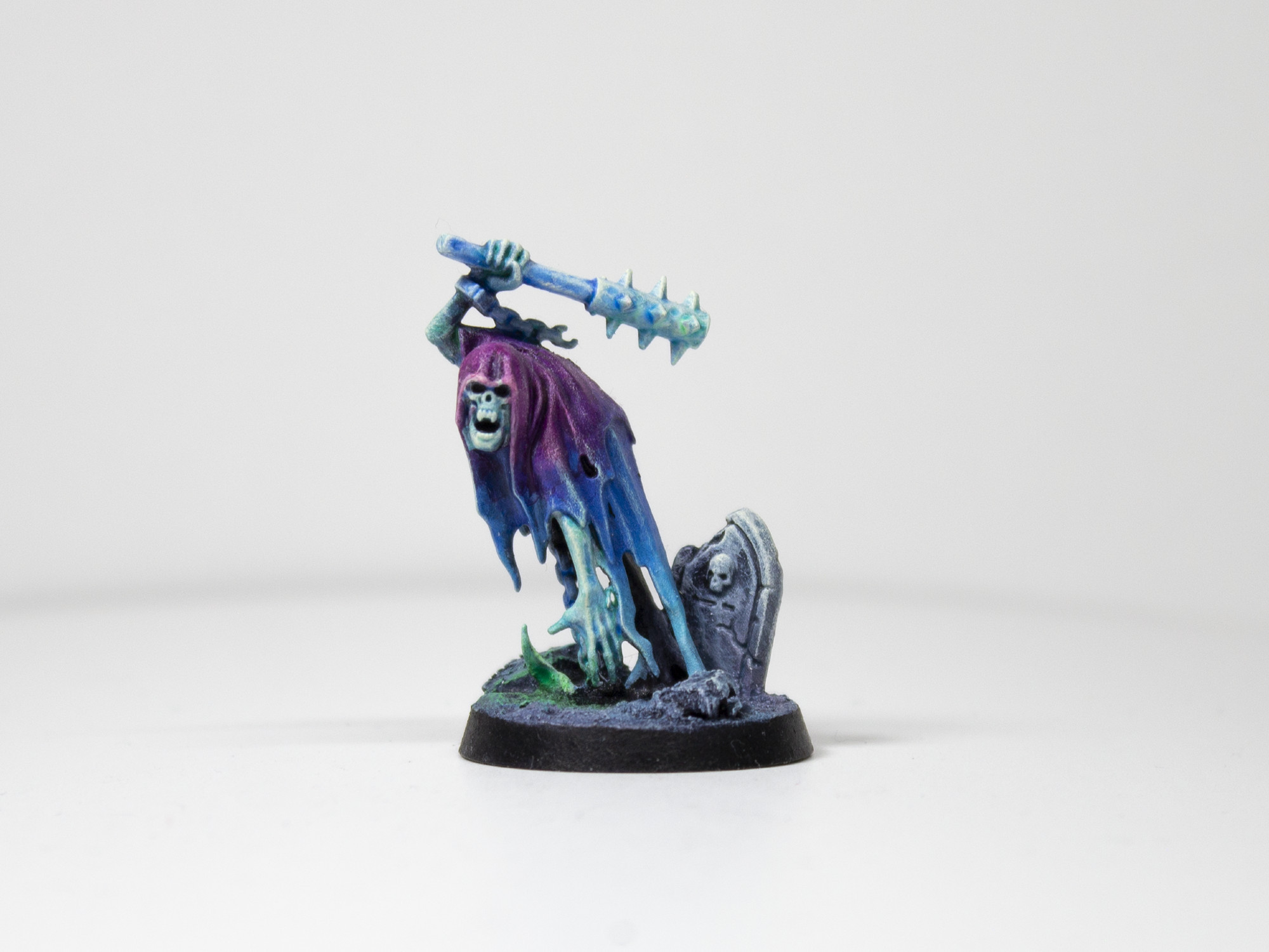 Painted miniature of a cloaked, ghastly figure raising a spiked club over its head. It is painted in a gradient from a bright purple to a lighter blue