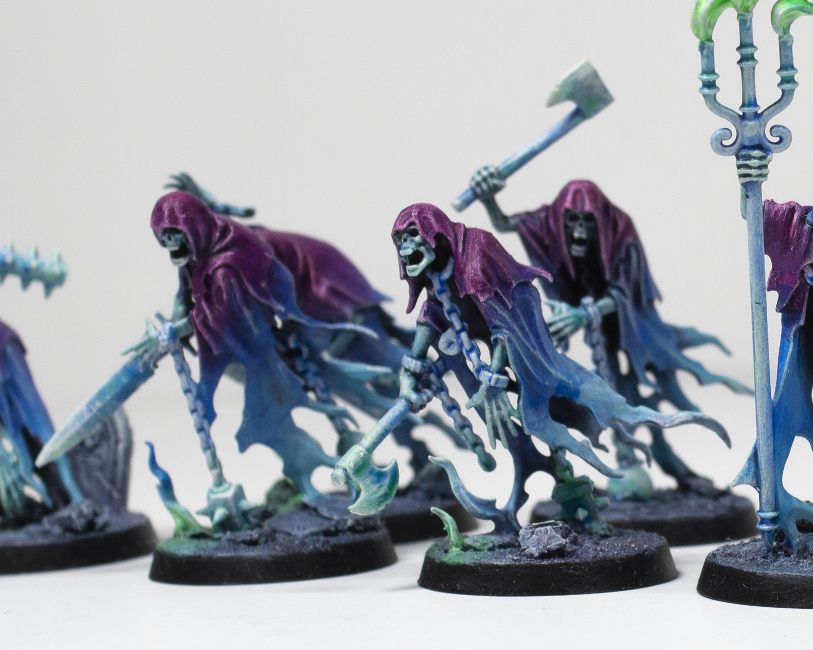 A lineup of various ghostly figures lunging forward and wielding weapons (Nighthaunts from Warhammer).