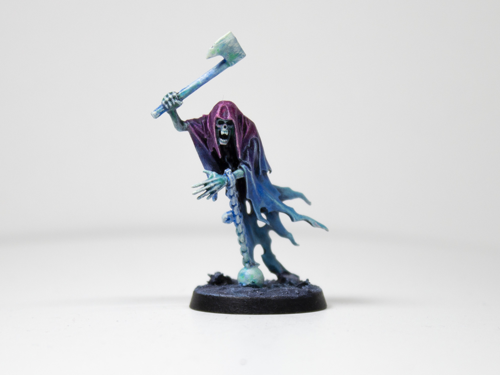 Painted miniature of a cloaked, ghastly figure raising an axe over its head. It is painted in a gradient from a bright purple to a lighter blue