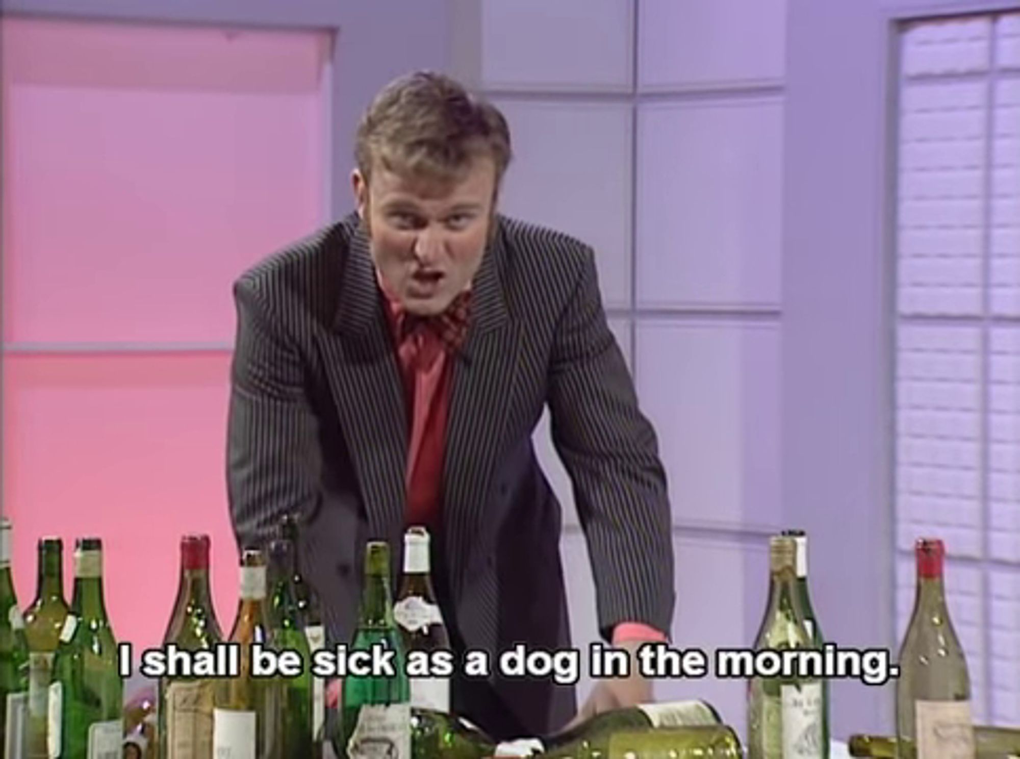 Hugh Dennis pretending to be a very drunk presenter on a Food and Drink programme.  The table in front of him has a large array of wine bottles, all empty.  He is looking into the camera, and saying "I shall be sick as a dog in the morning".