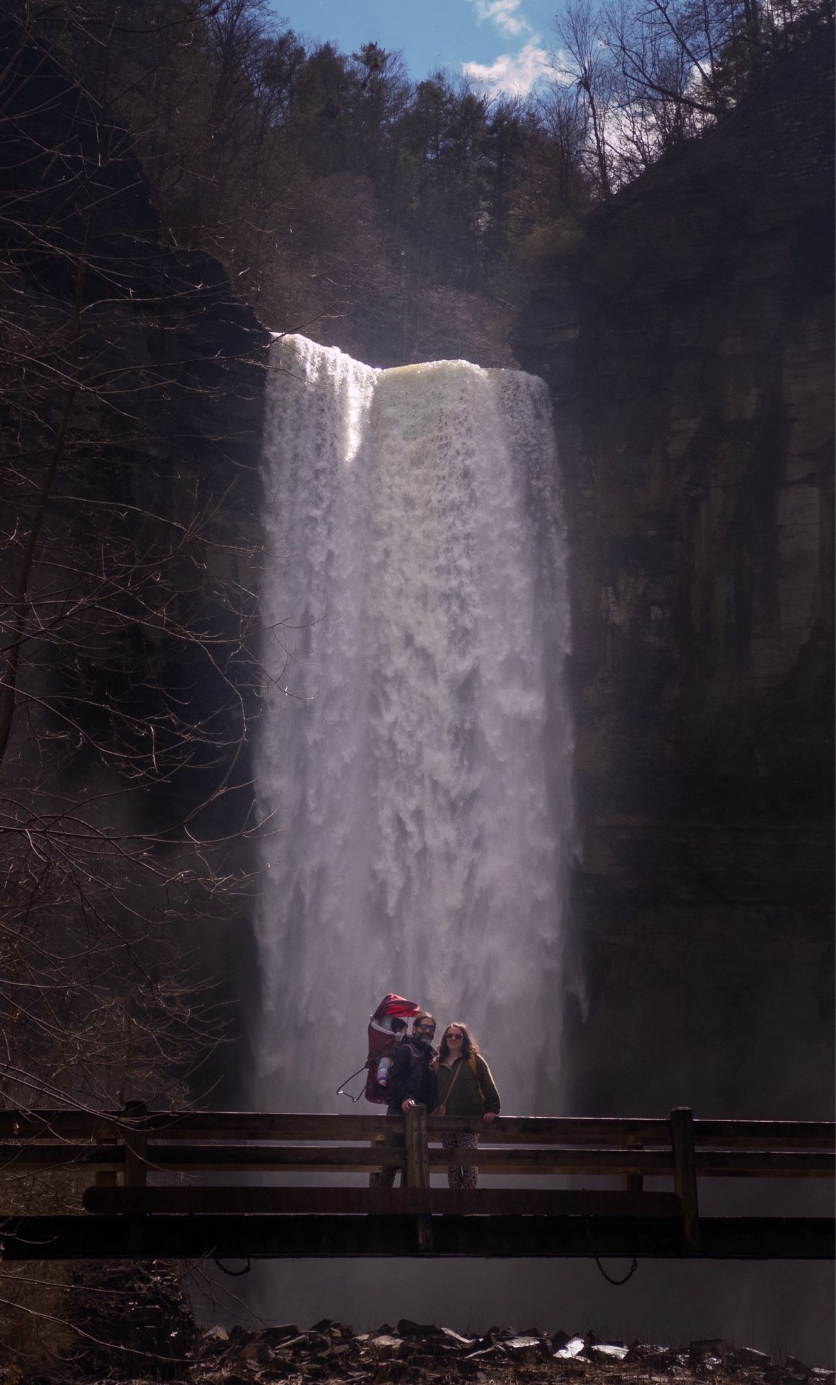 Photo of a couple + baby in front of a large waterfall