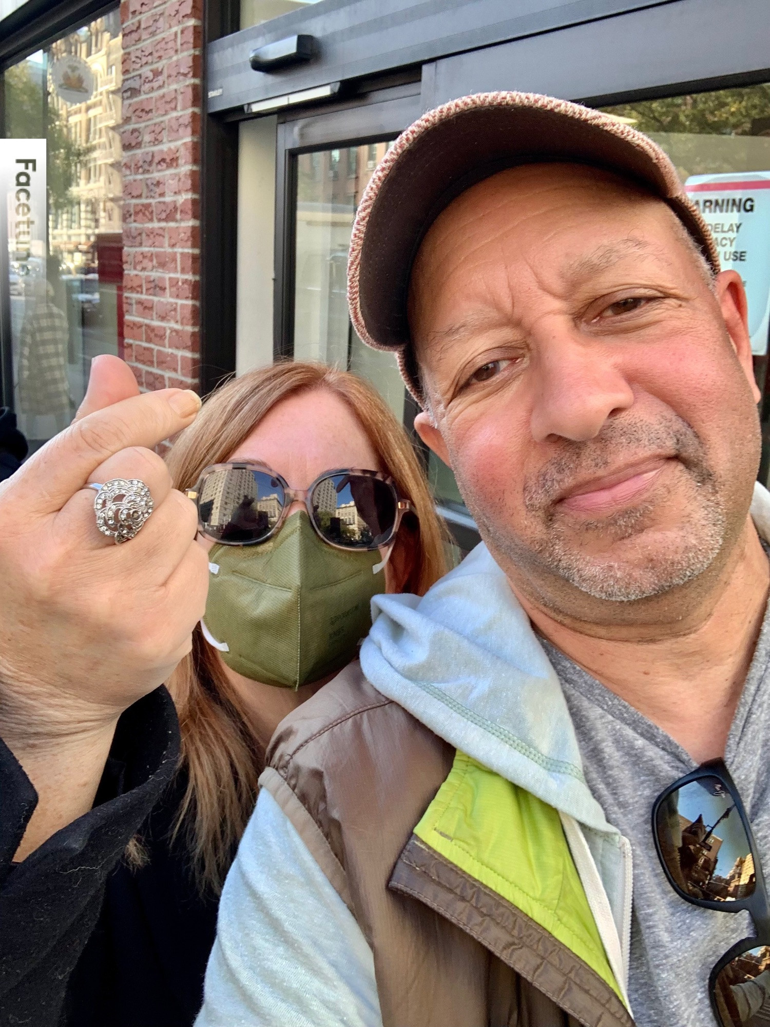 Carl Phillips and Erin Belieu on the street in the West Village. Erin is making heart sign with finger and thumb