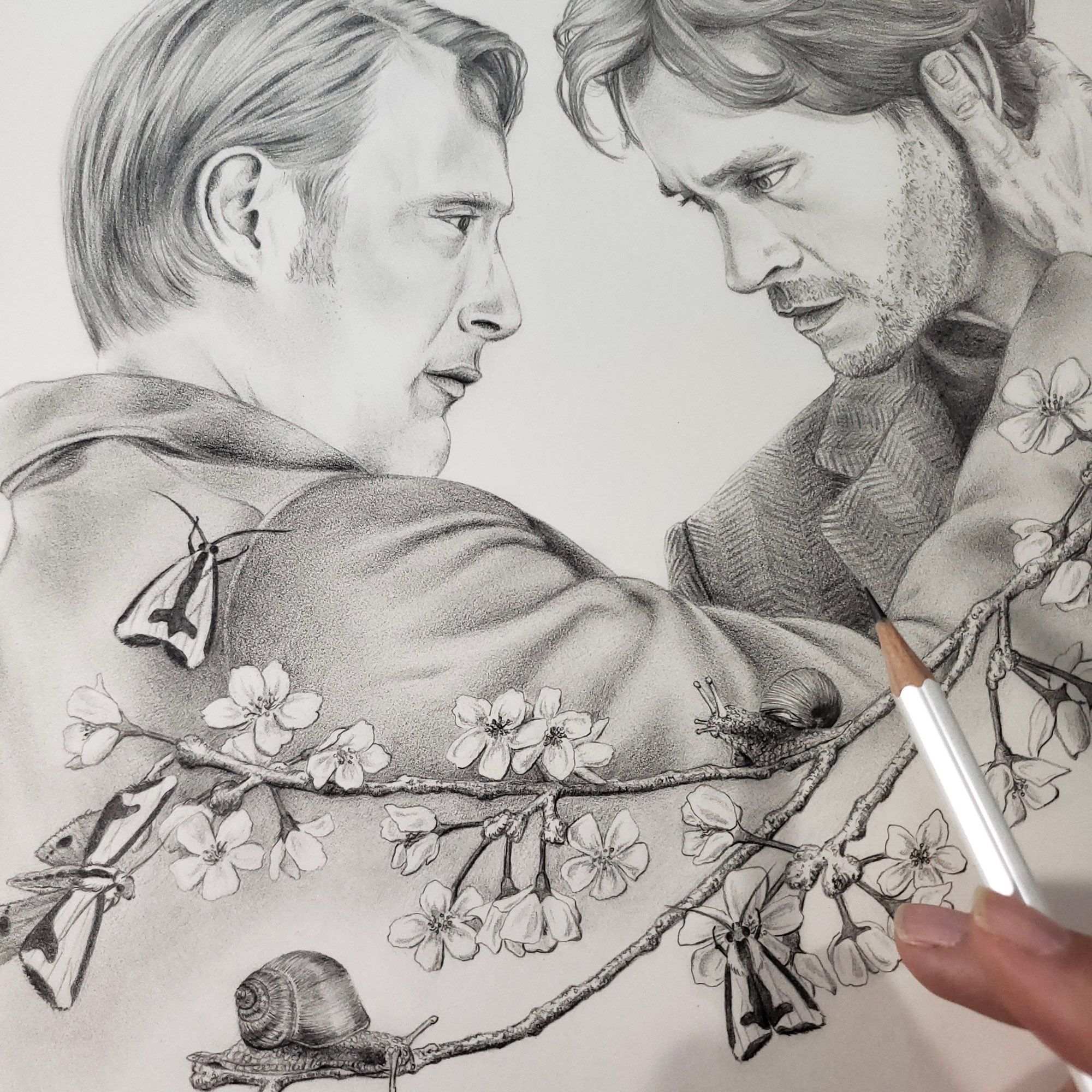 Graphite drawing of Hannibal and Will Graham embraced by cherry blossom branches, with snails and moths. A hand holding a pencil hovers above it on the bottom right. 