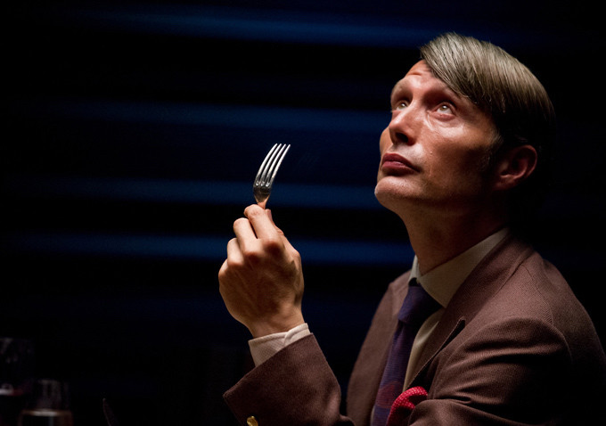 Hannibal Lecter holding a fork, looking up, possibly thinking about a menu that involved TERFs.