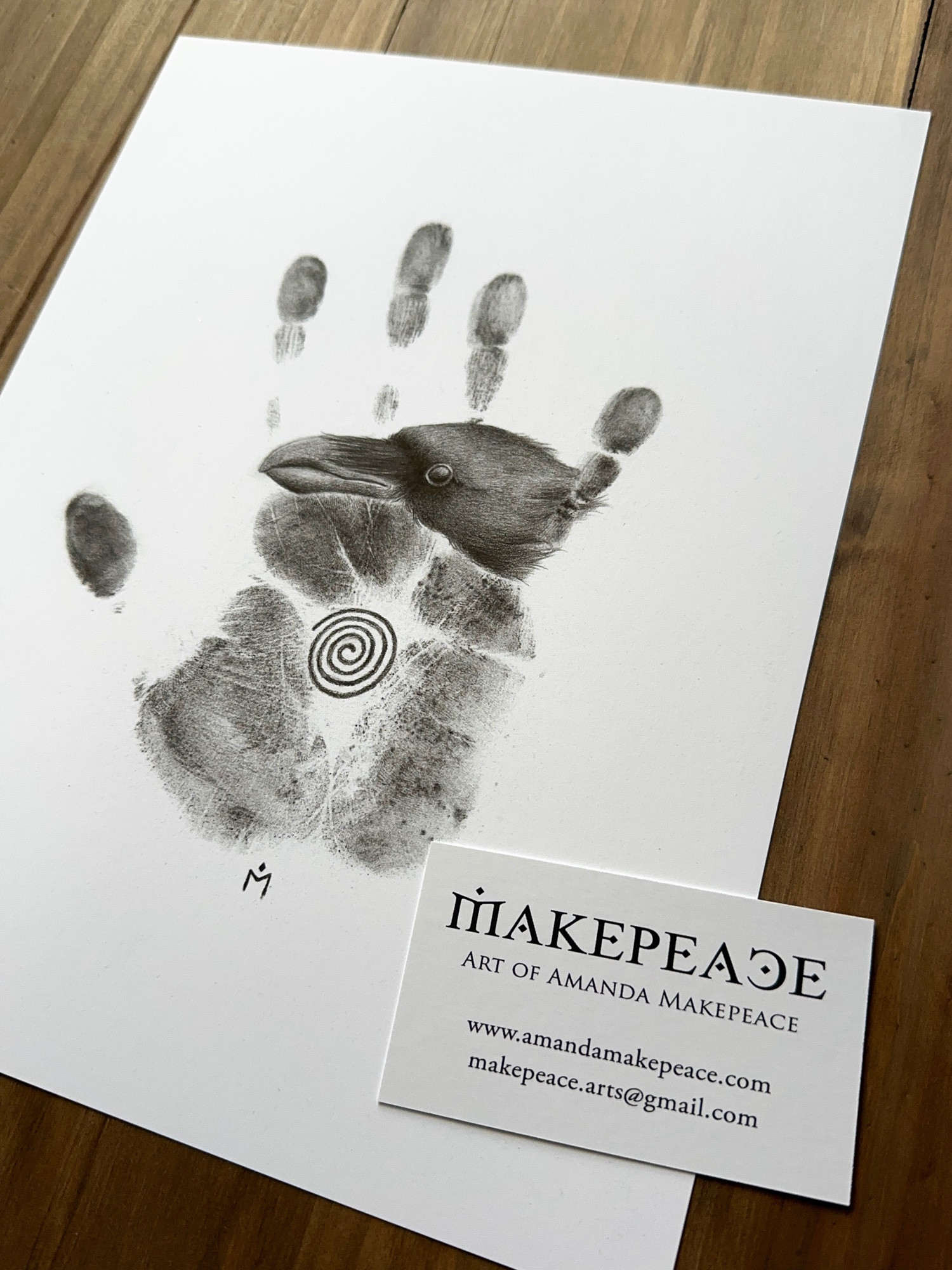 Print of my drawing Ancestral 1, handprint in graphite powder with a raven’s head emerging, a spiral in the palm